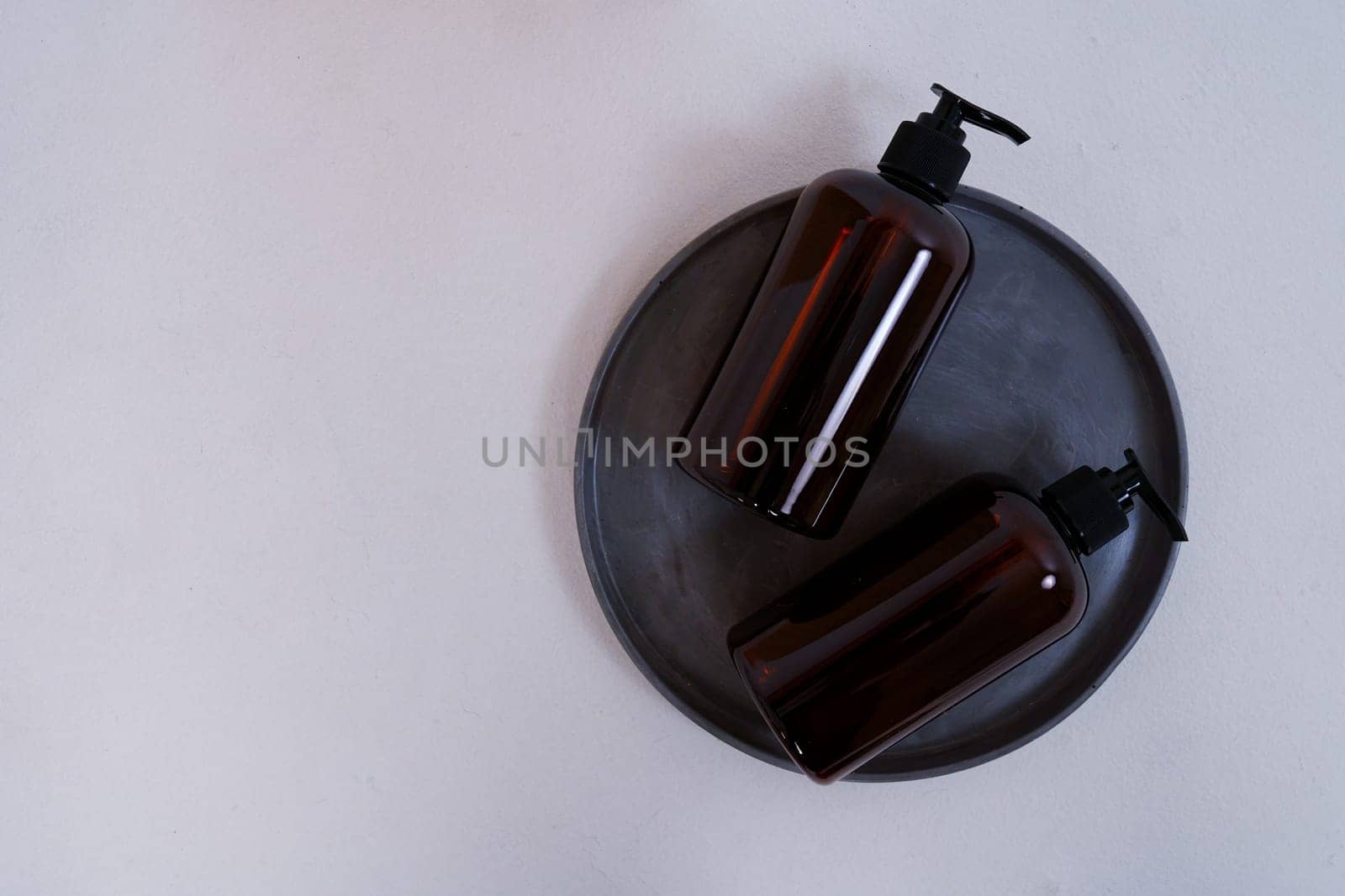 Composition with geometric shapes. Body care. two bottles with a dispenser on a black plate on a light gray background. Advertising concept. High quality photo