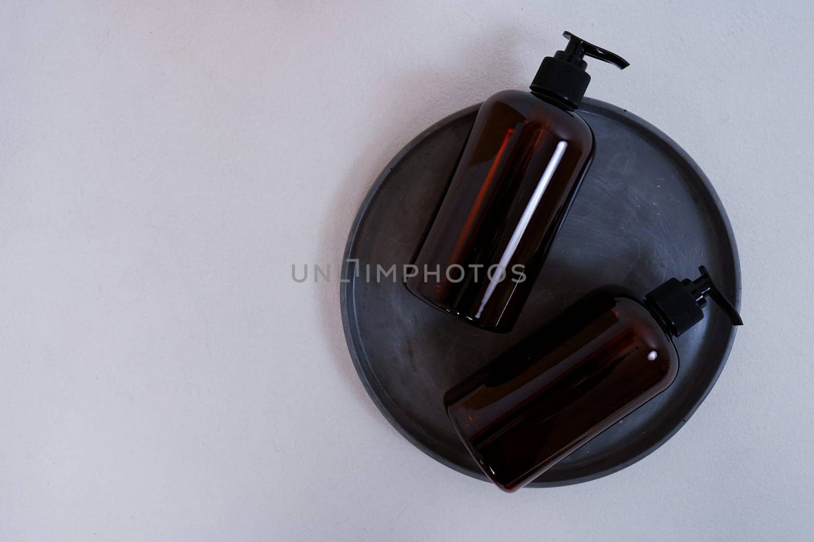 Composition with geometric shapes. Body care. two bottles with a dispenser on a black plate on a light gray background. Advertising concept by tewolf