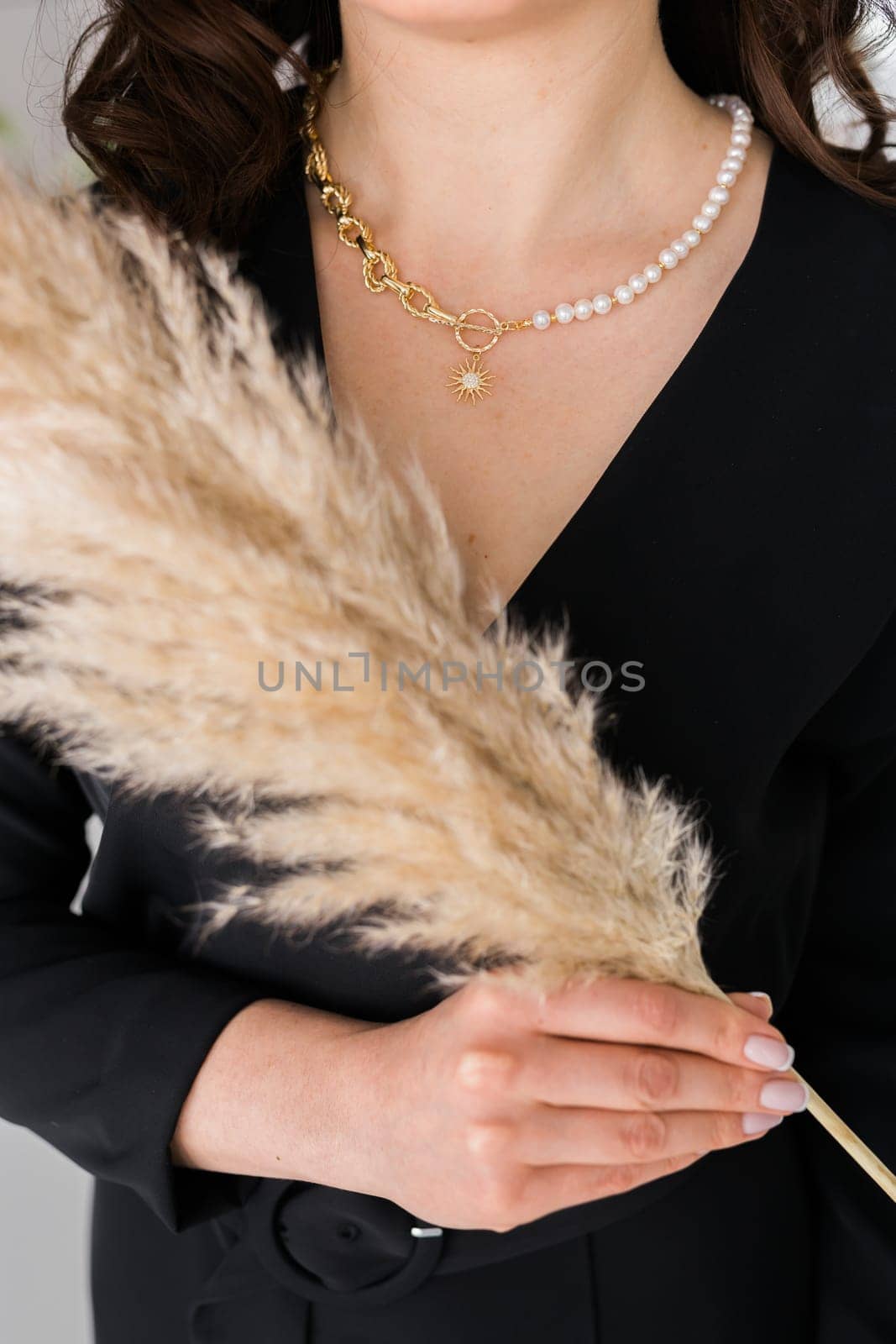 Close-up female in modern gold metal necklace chain with pearl pendant.