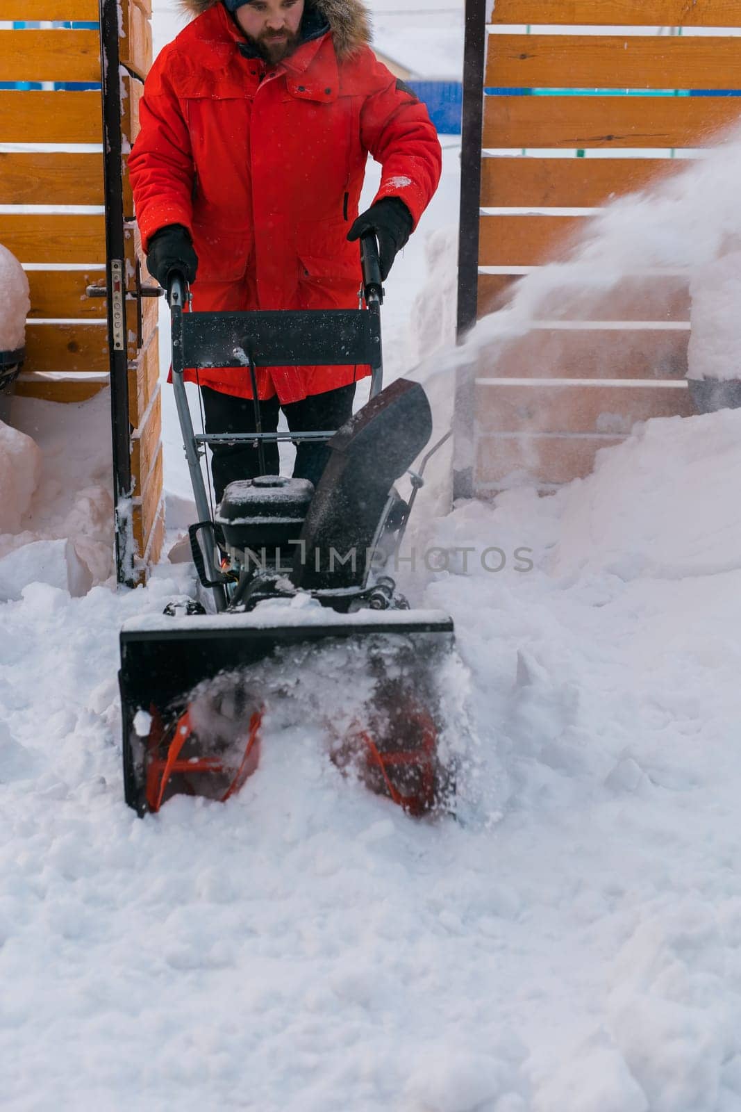 A man clear snow from backyard with snow blower. Winter season and snow blower equipment.