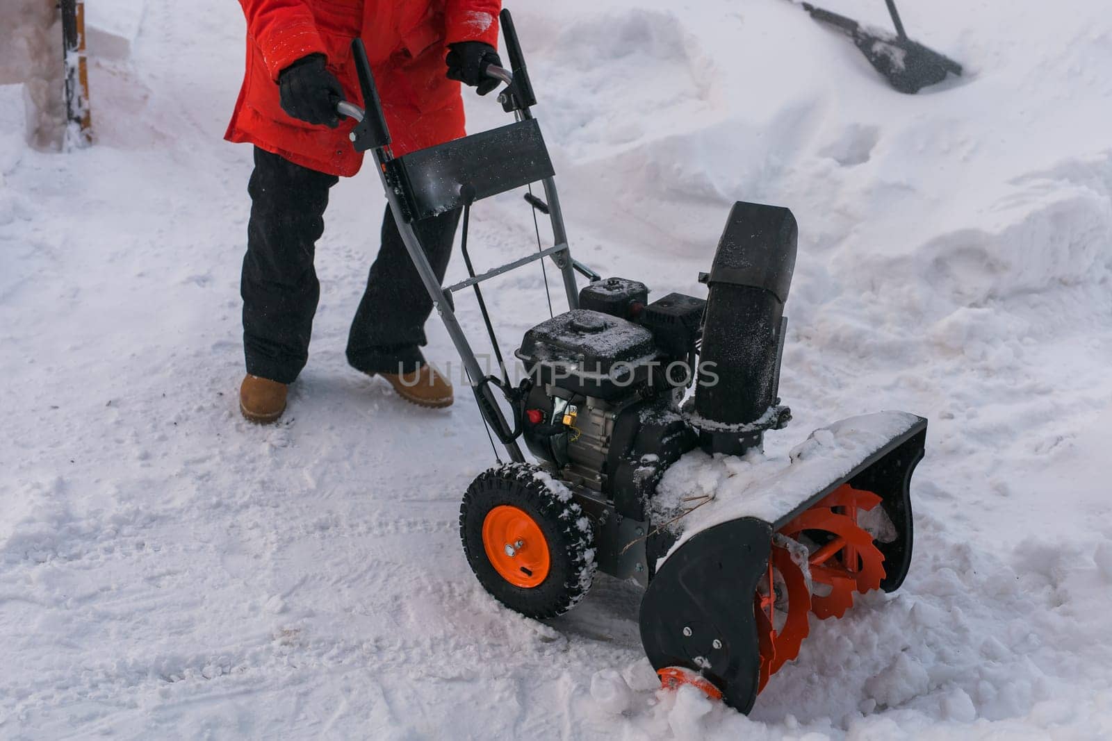A man clear snow from backyard with snow blower close-up. Winter season and snow blower equipment close-up by Satura86