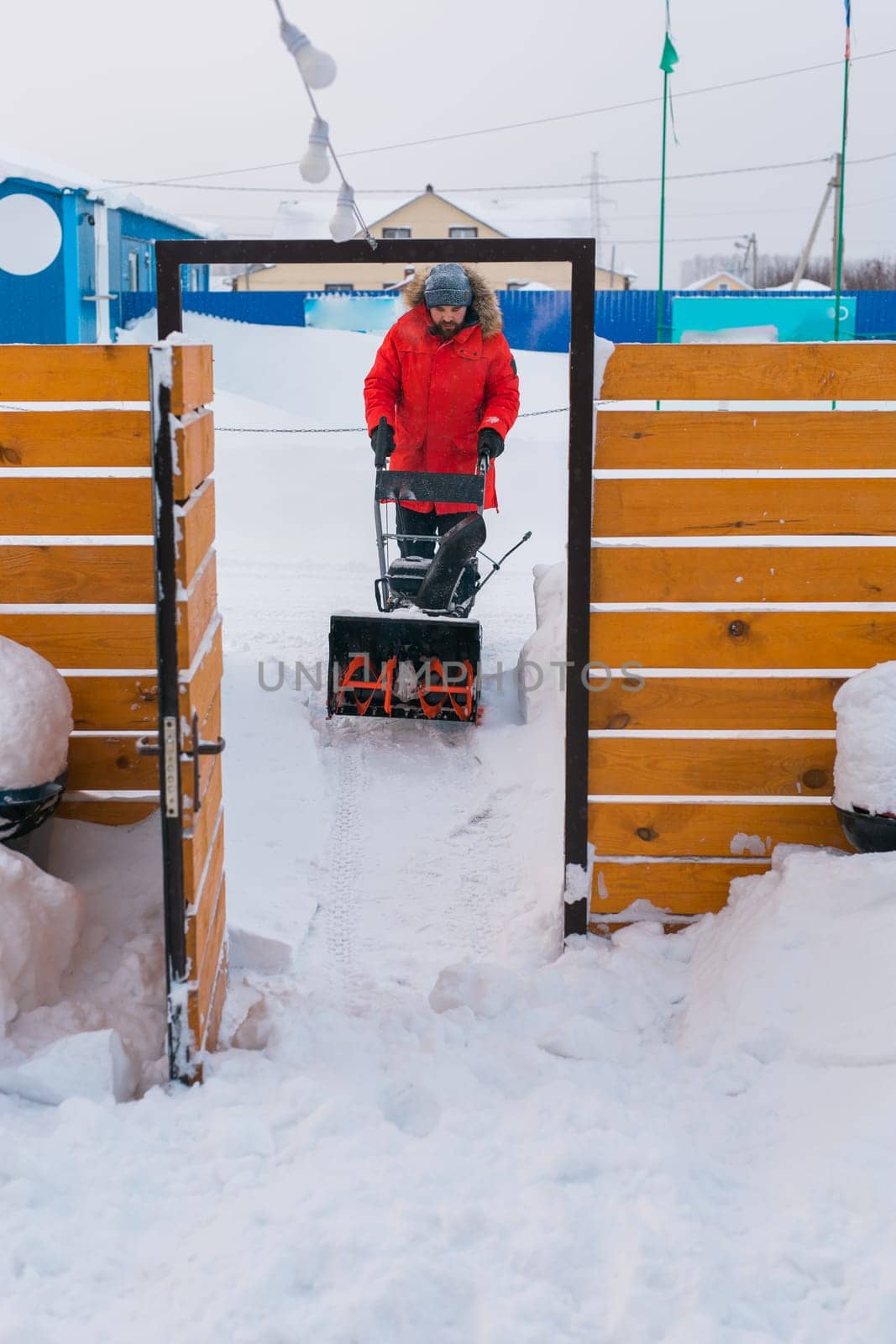 A man clear snow from backyard with snow blower. Winter season and snow blower equipment.