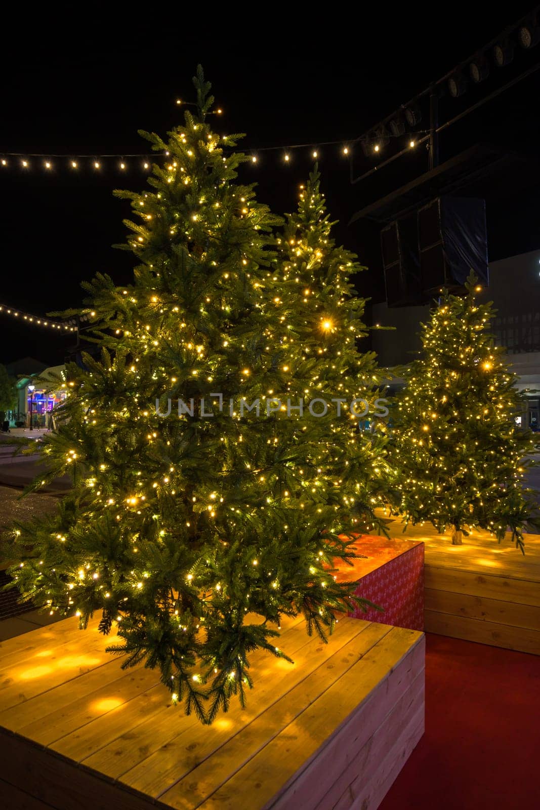 Christmas tree in pot with red decorations and lights outdoors near grey loft building by carlosviv