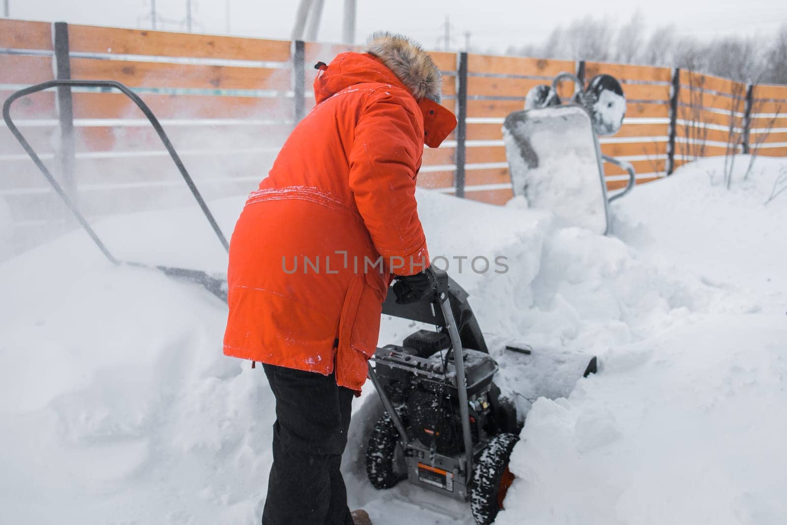 A man clear snow from backyard with snow blower. Winter season and snow blower equipment by Satura86