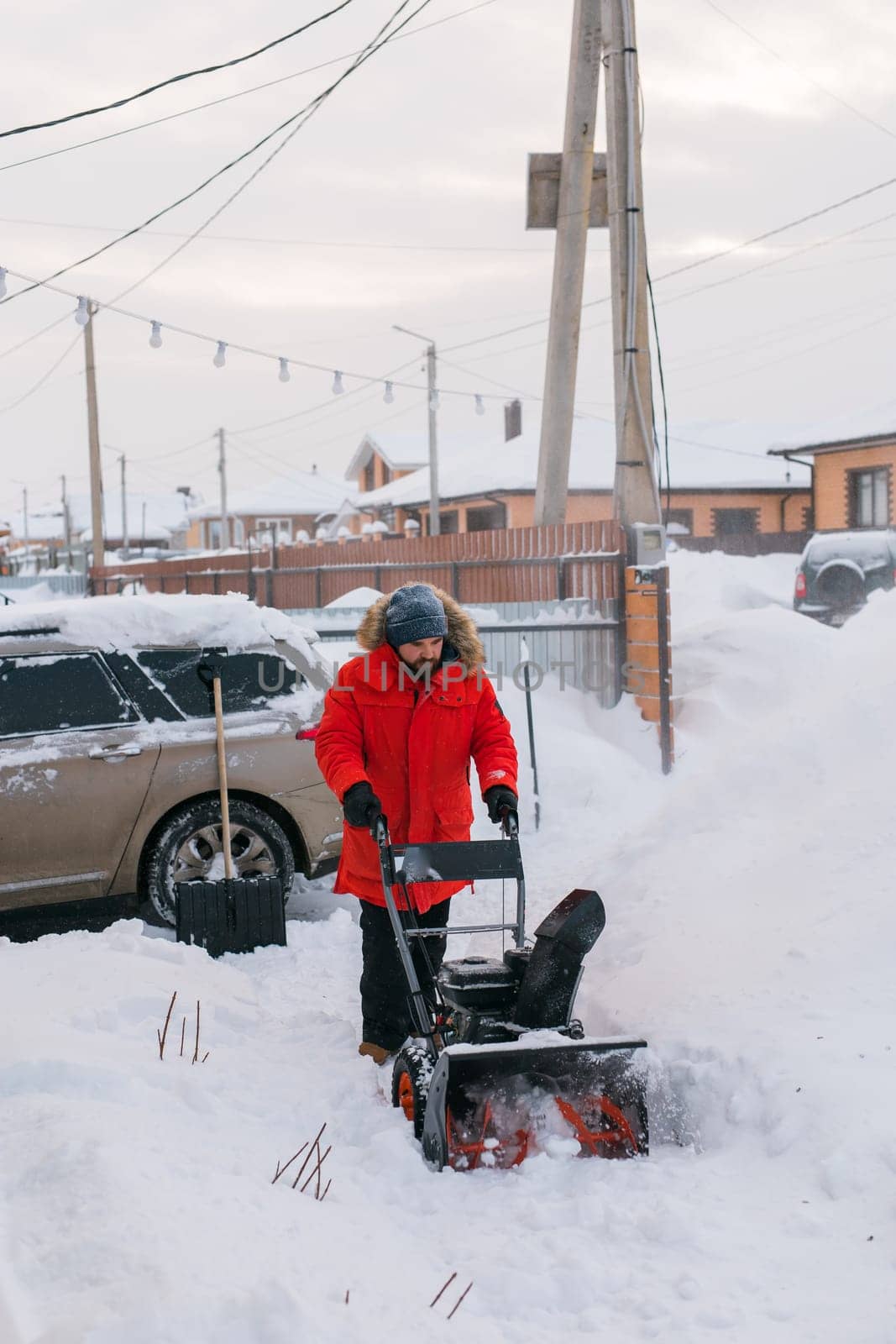 A man clear snow from backyard with snow blower. Winter season and snow blower equipment.