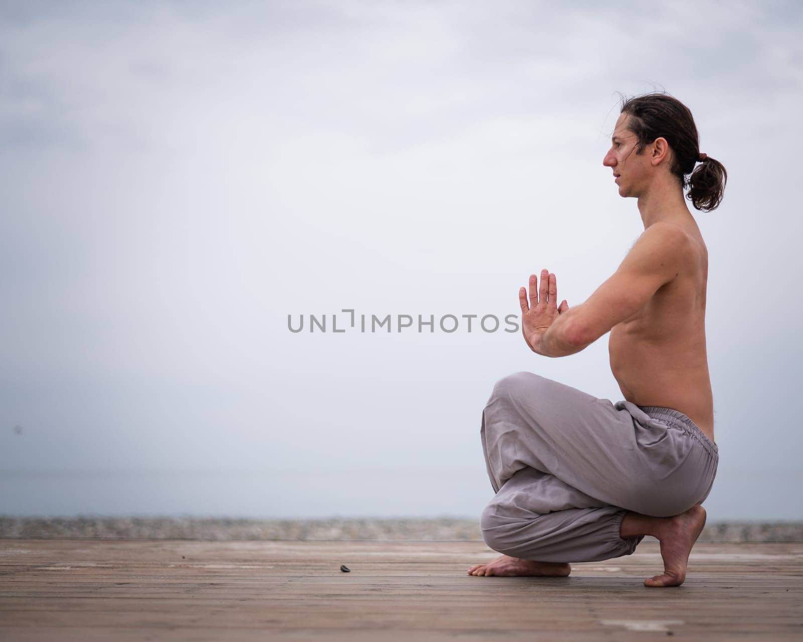 Caucasian man with naked torso practicing wushu on the seashore. by mrwed54
