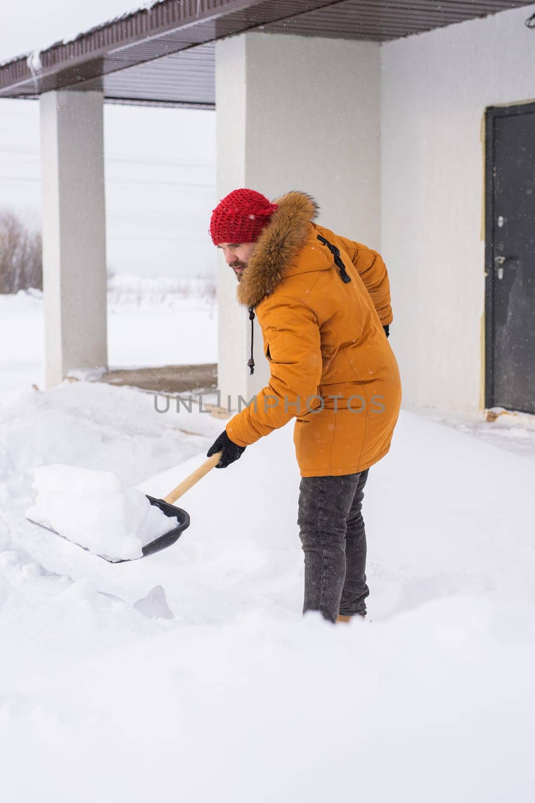 Man removing snow and ice from the sidewalk in front of house. Winter season by Satura86