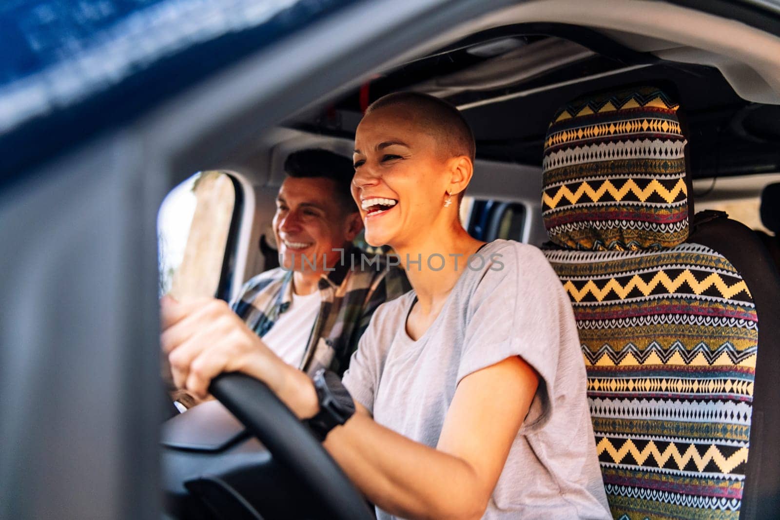 couple laughing happy during their route through the countryside in camper van, concept of adventure travel and active tourism in nature