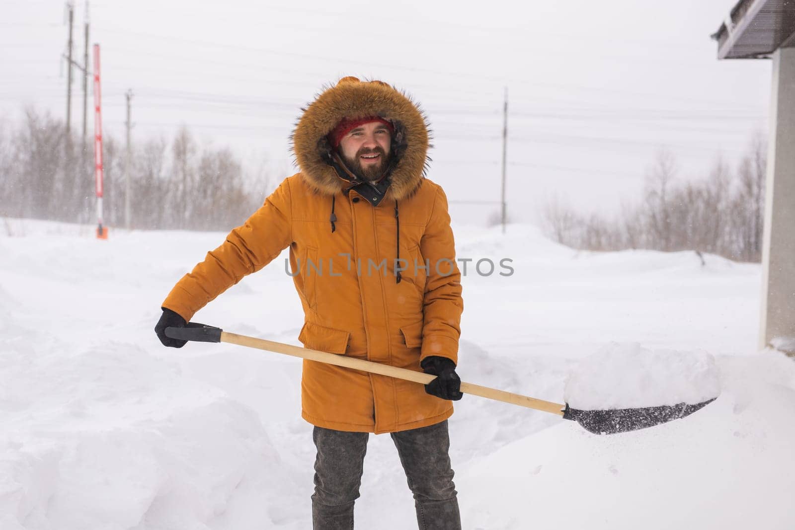 Young man clearing snow in his backyard village house with shovel. Remove snow from the sidewalk