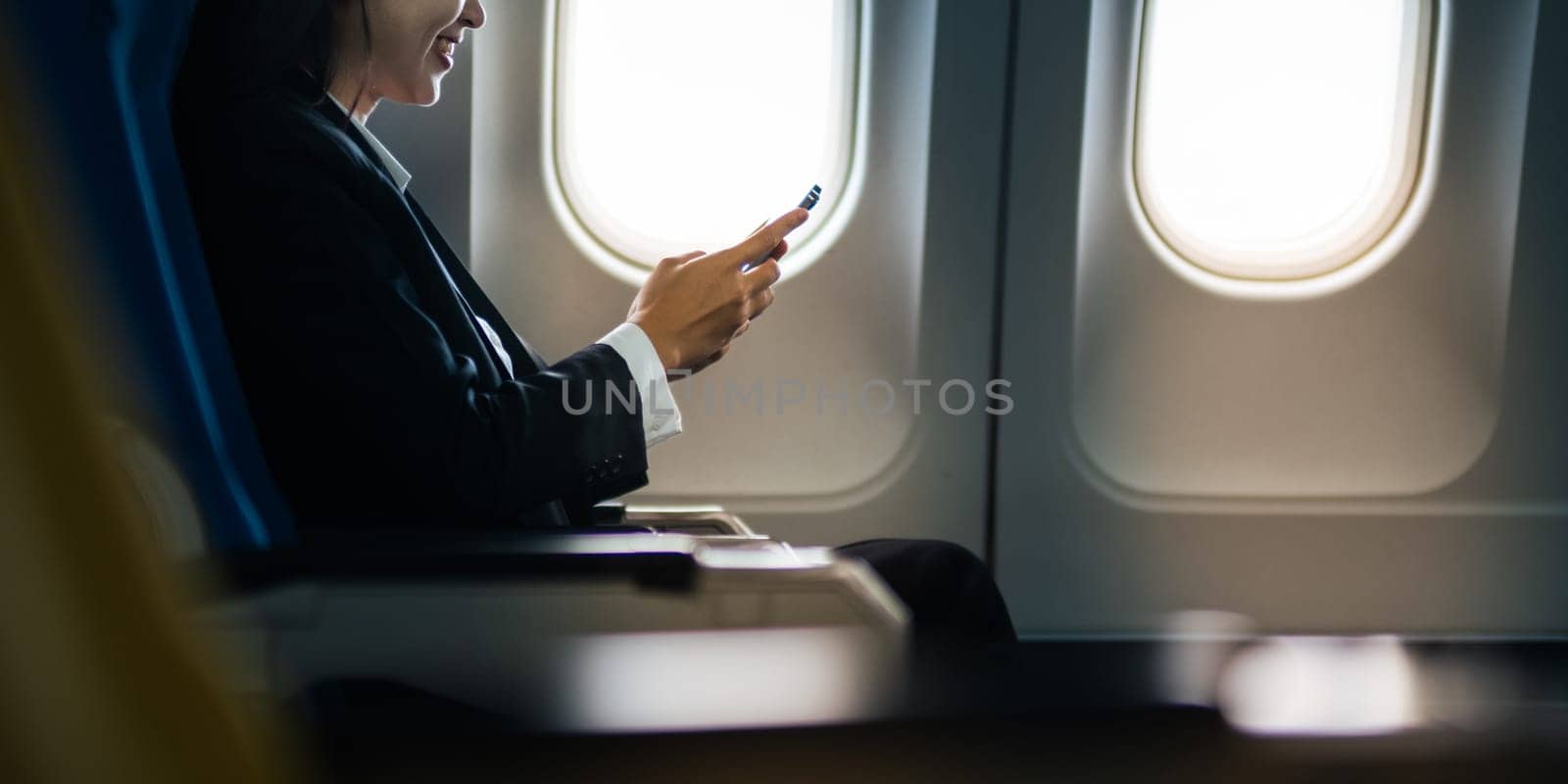 Traveling and technology. flying at first class. pretty young asian business woman using smartphone while sitting in airplane.