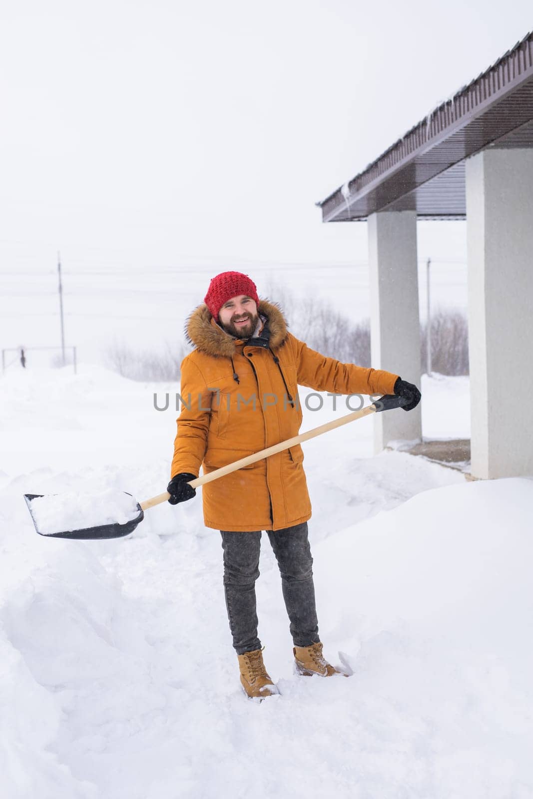 Man is clearing the snow near house and on staircases hovelling at the winter season. Winter storm and season specific.