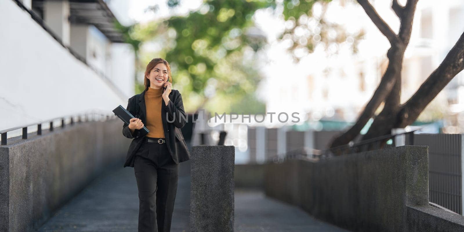 Successful business woman talking on mobile outdoor. beautiful woman going to working with coffee walking near office building. by nateemee