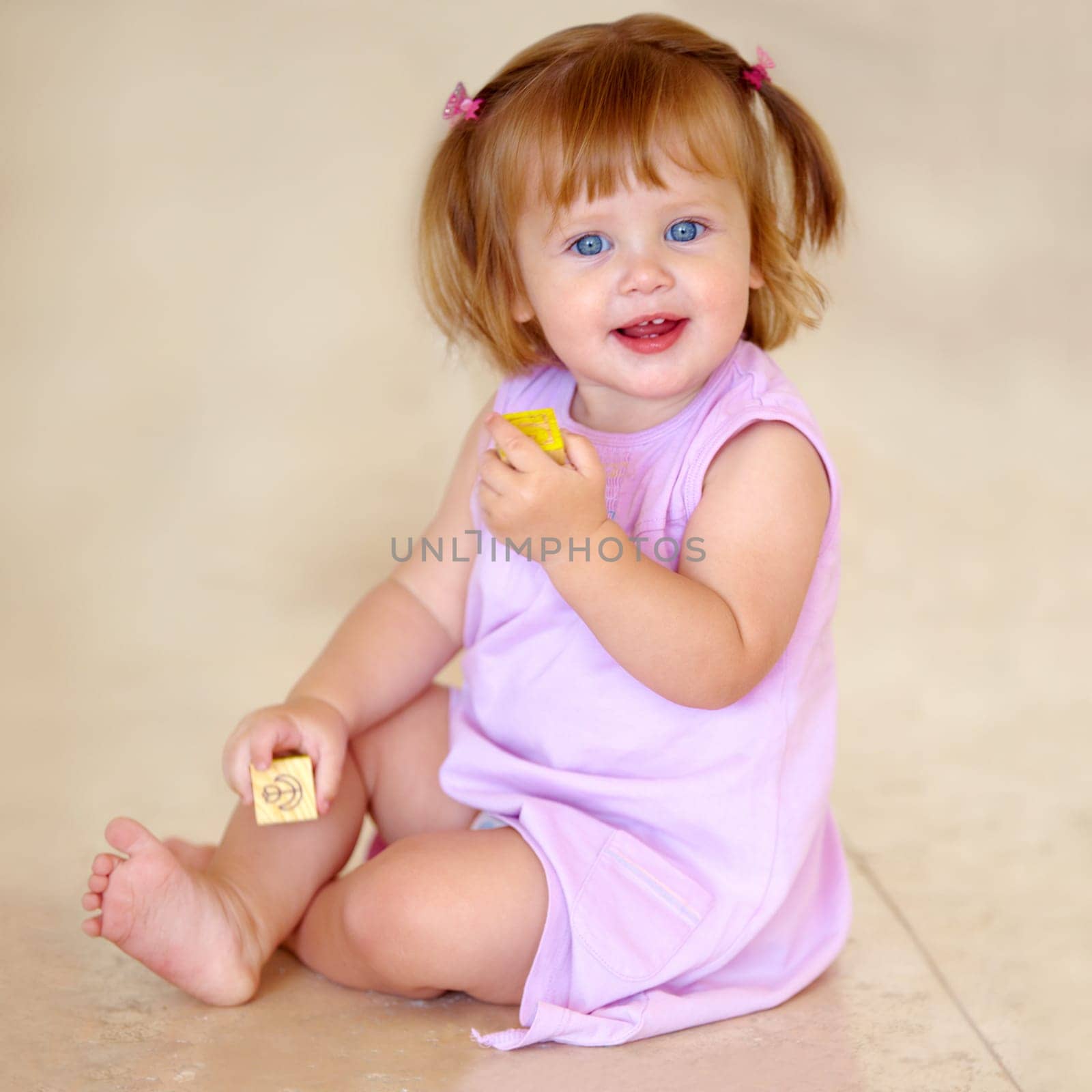 Portrait, toddler or little girl with toy in home for motor skills, child development or growth. Happy kid, cute and trendy hairstyle with hand holding for block for grip with milestone for future.