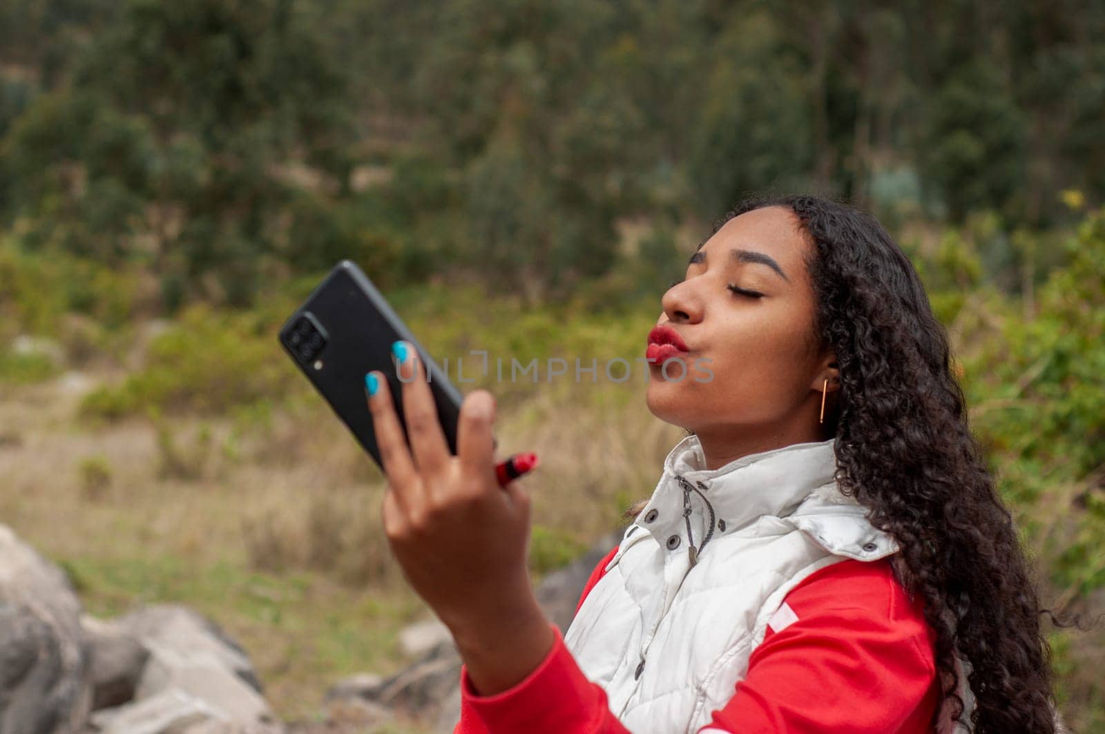 latin american vlogger girl sends a kiss to her followers during a live show on a mountain by Raulmartin