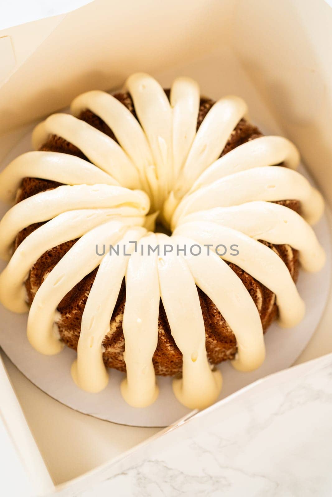 The freshly baked bundt cakes are carefully nestled into white paper boxes, preparing them for secure transportation while maintaining their delectable appearance.