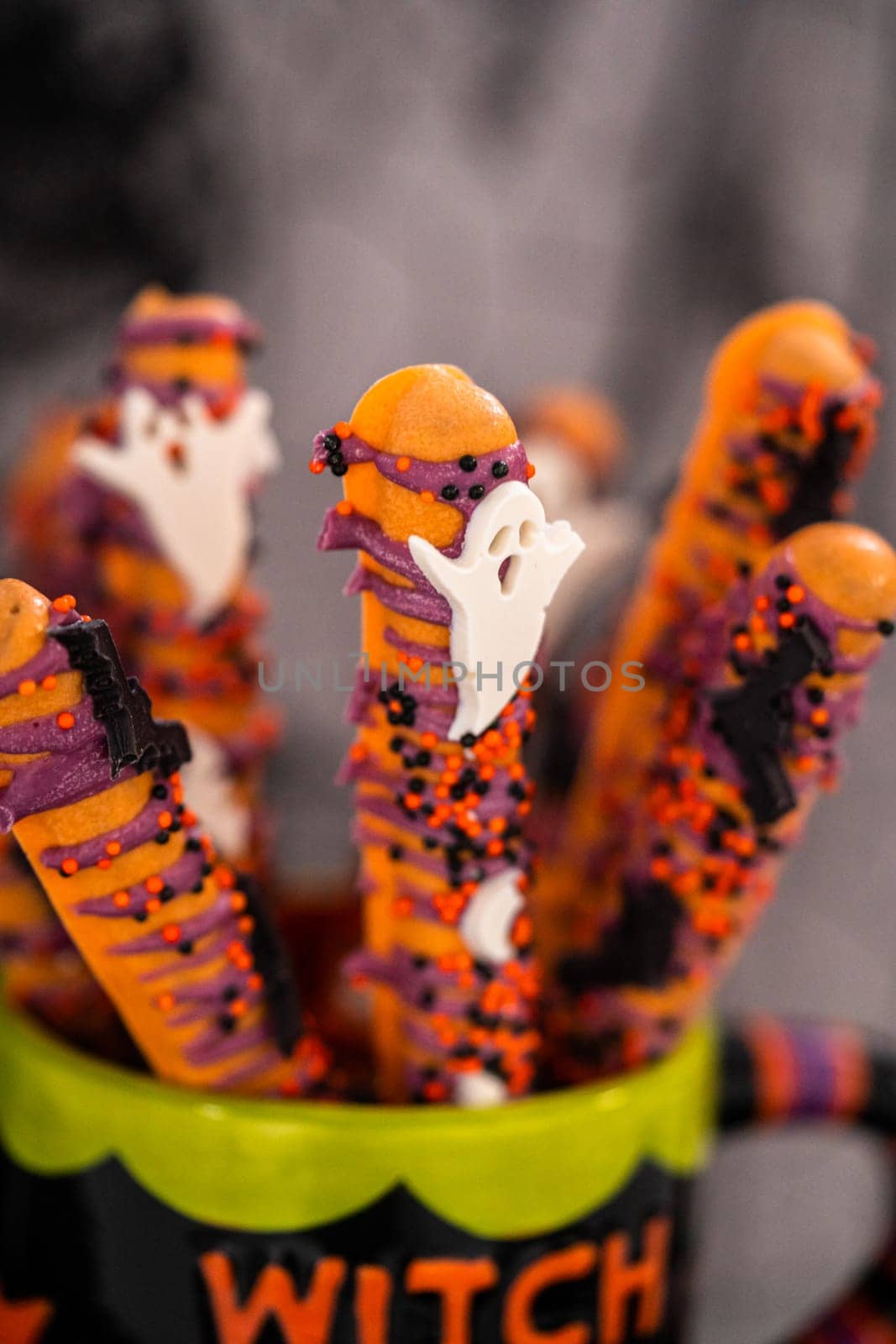 Halloween chocolate-covered pretzel rods with sprinkles in a cup.