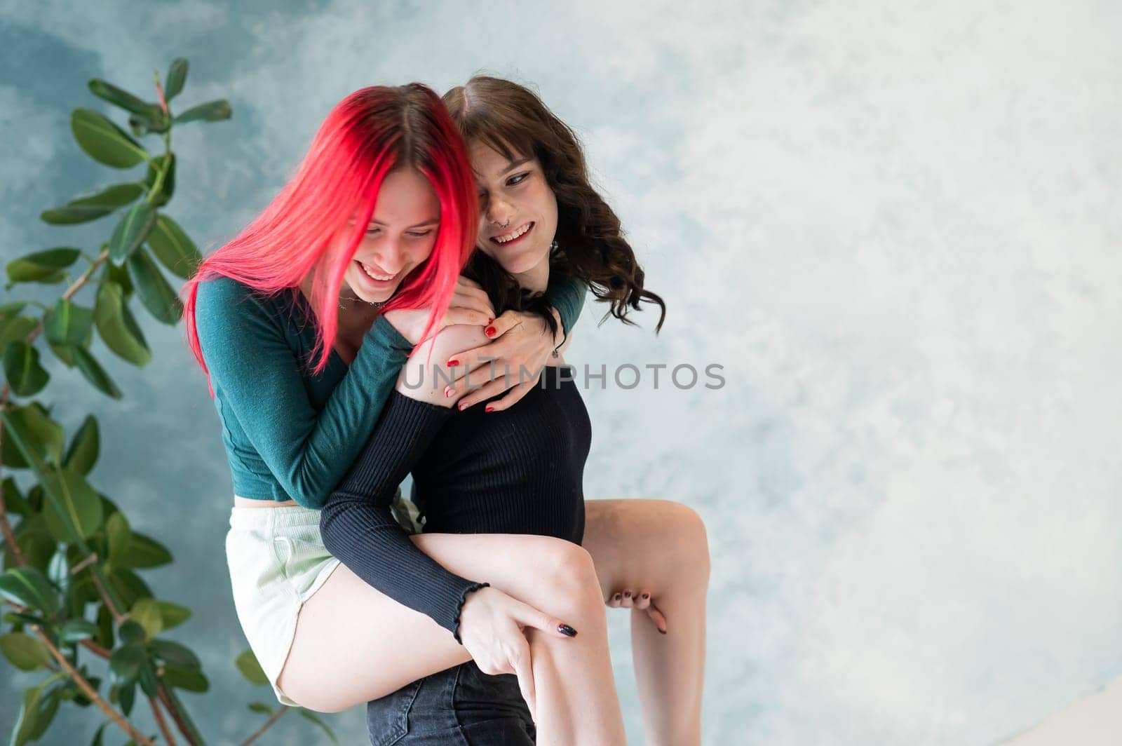 Two friends are fooling around. Young caucasian woman on the back of another