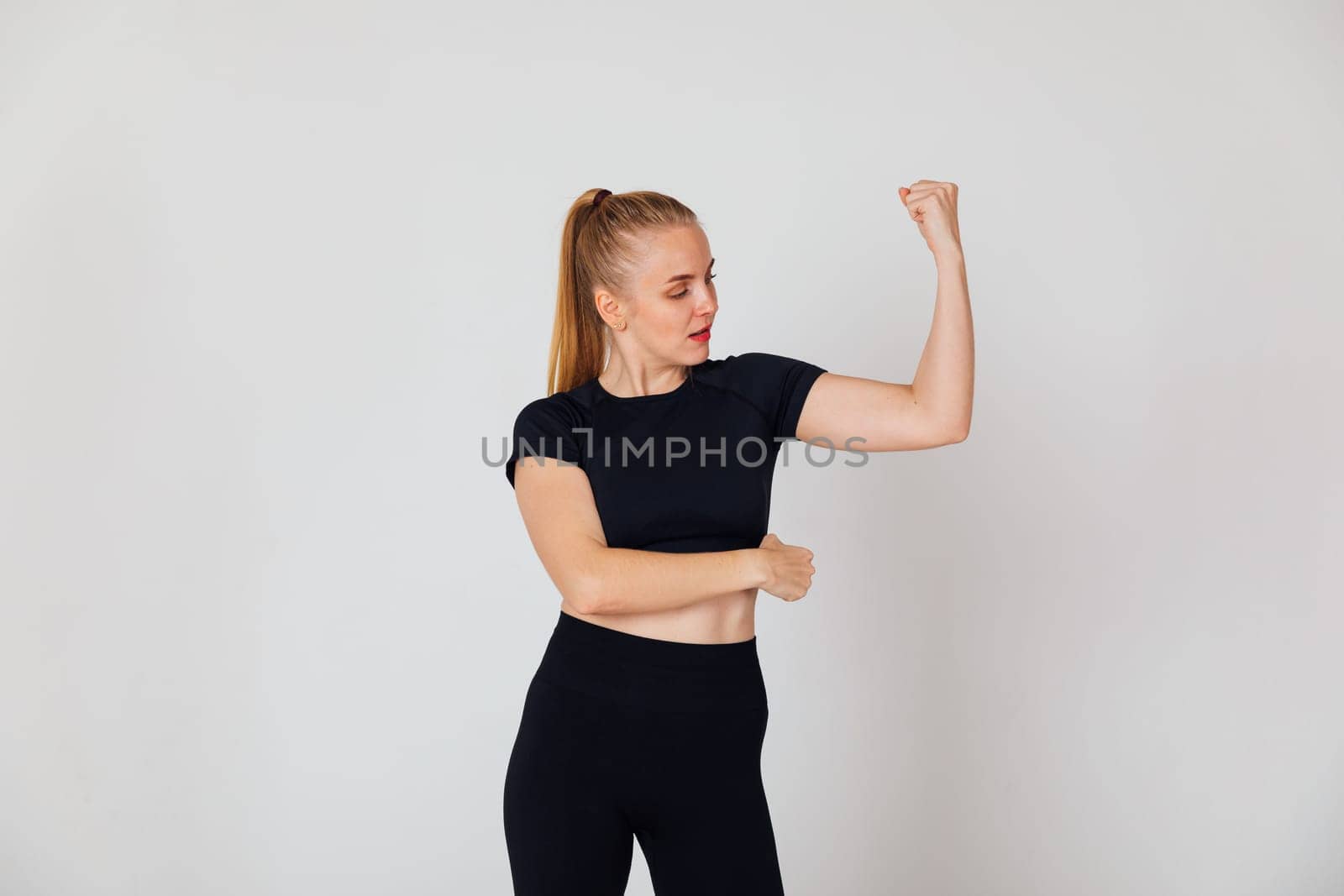 Woman showing biceps on arm on background