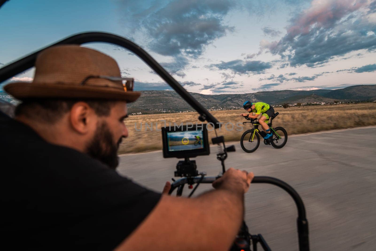 A videographer recording a triathlete riding his bike preparing for an upcoming marathon.Athlete's physical endurance and the dedication required to succeed in the sport. by dotshock