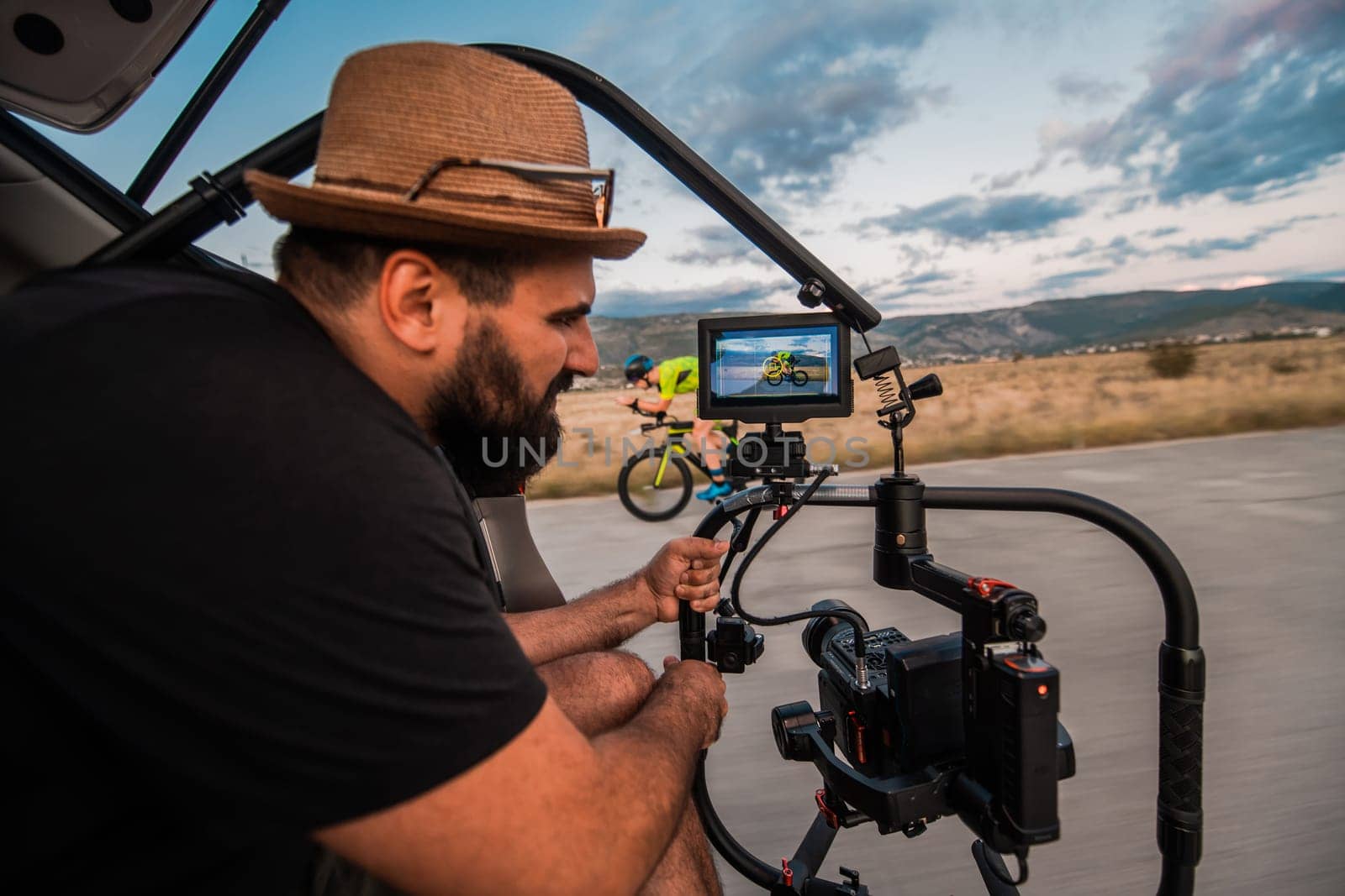 A videographer recording a triathlete riding his bike preparing for an upcoming marathon.Athlete's physical endurance and the dedication required to succeed in the sport. by dotshock