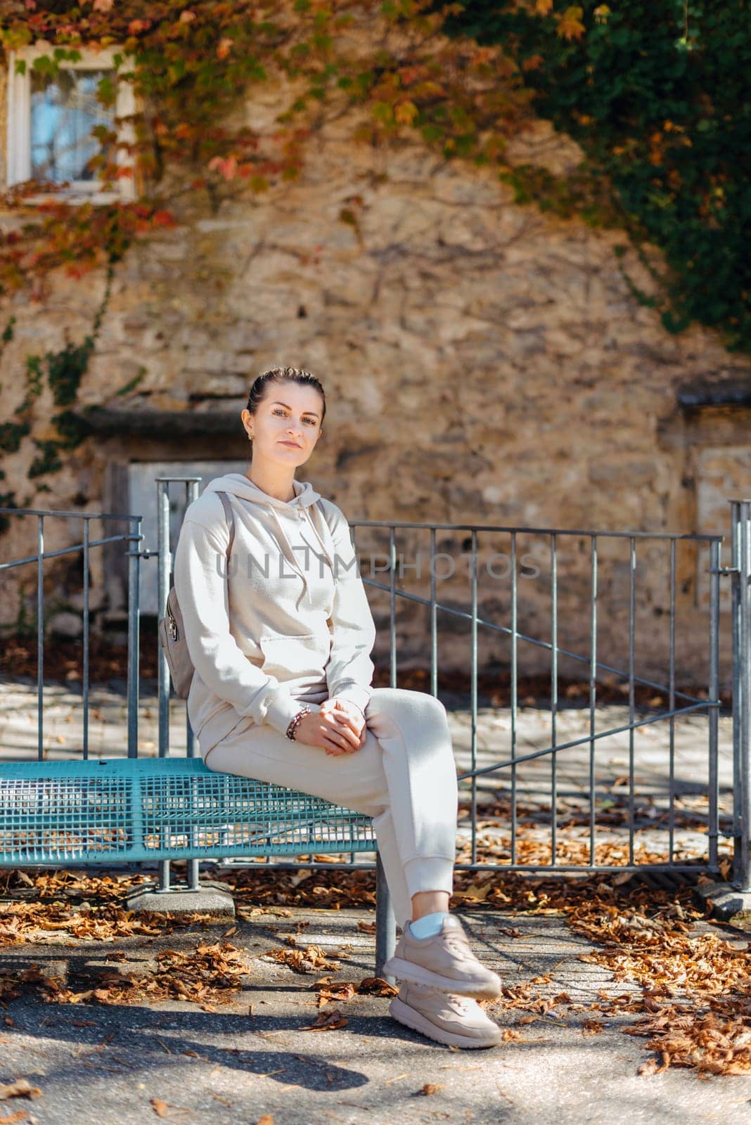 Attractive young woman sitting on a bench enjoying a view of medieval town in Europe. Summer holidays concept.