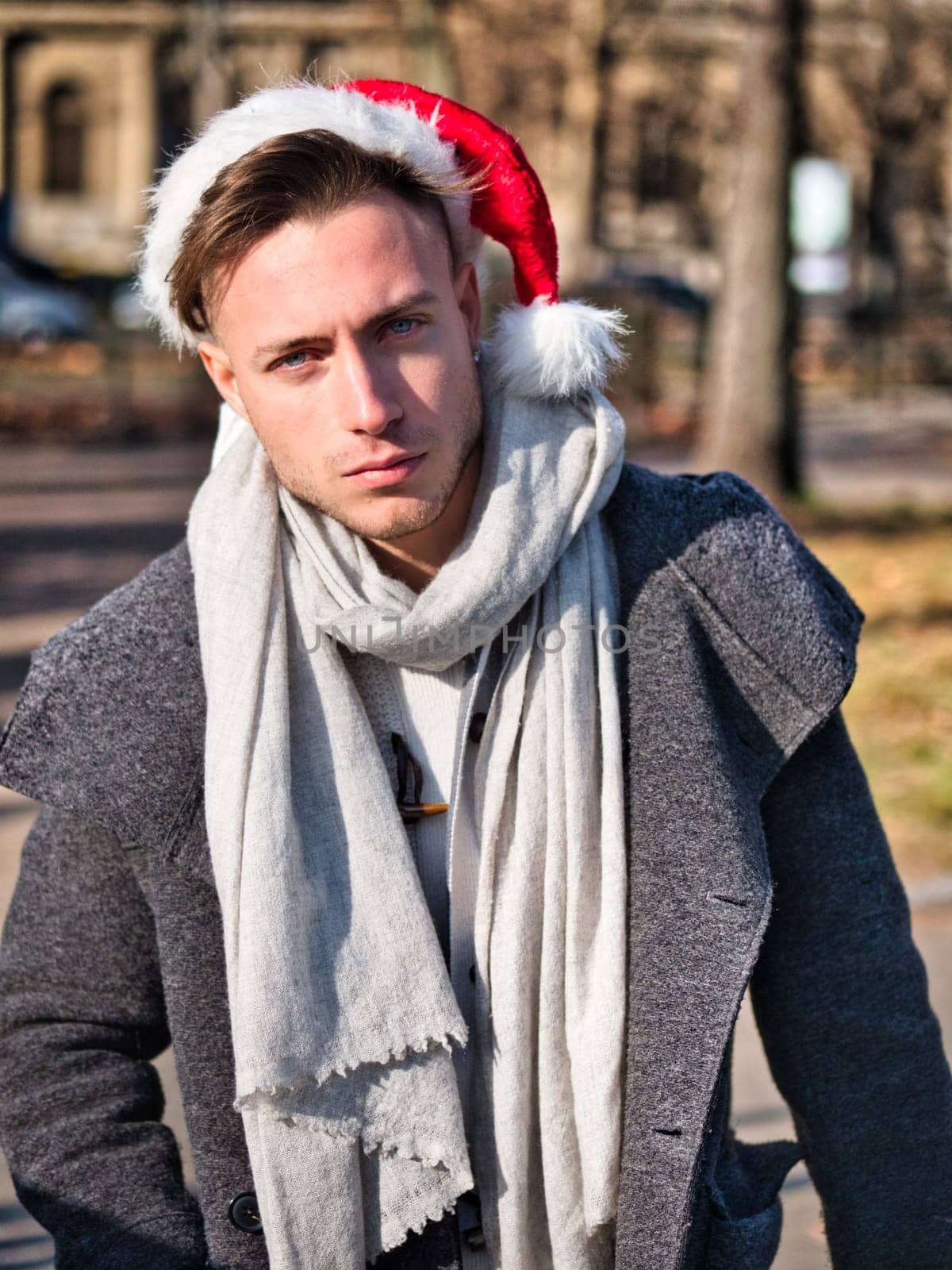 Young Handsome Man in Santa Claus Hat on Street by artofphoto