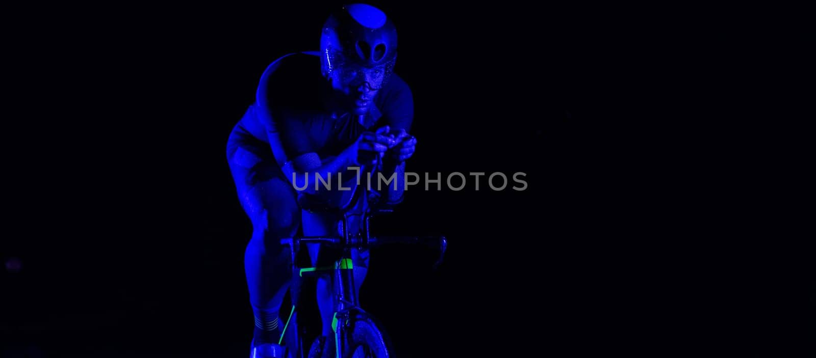 A triathlete rides his bike in the darkness of night, pushing himself to prepare for a marathon. The contrast between the darkness and the light of his bike creates a sense of drama and highlights the athlete's determination and perseverance