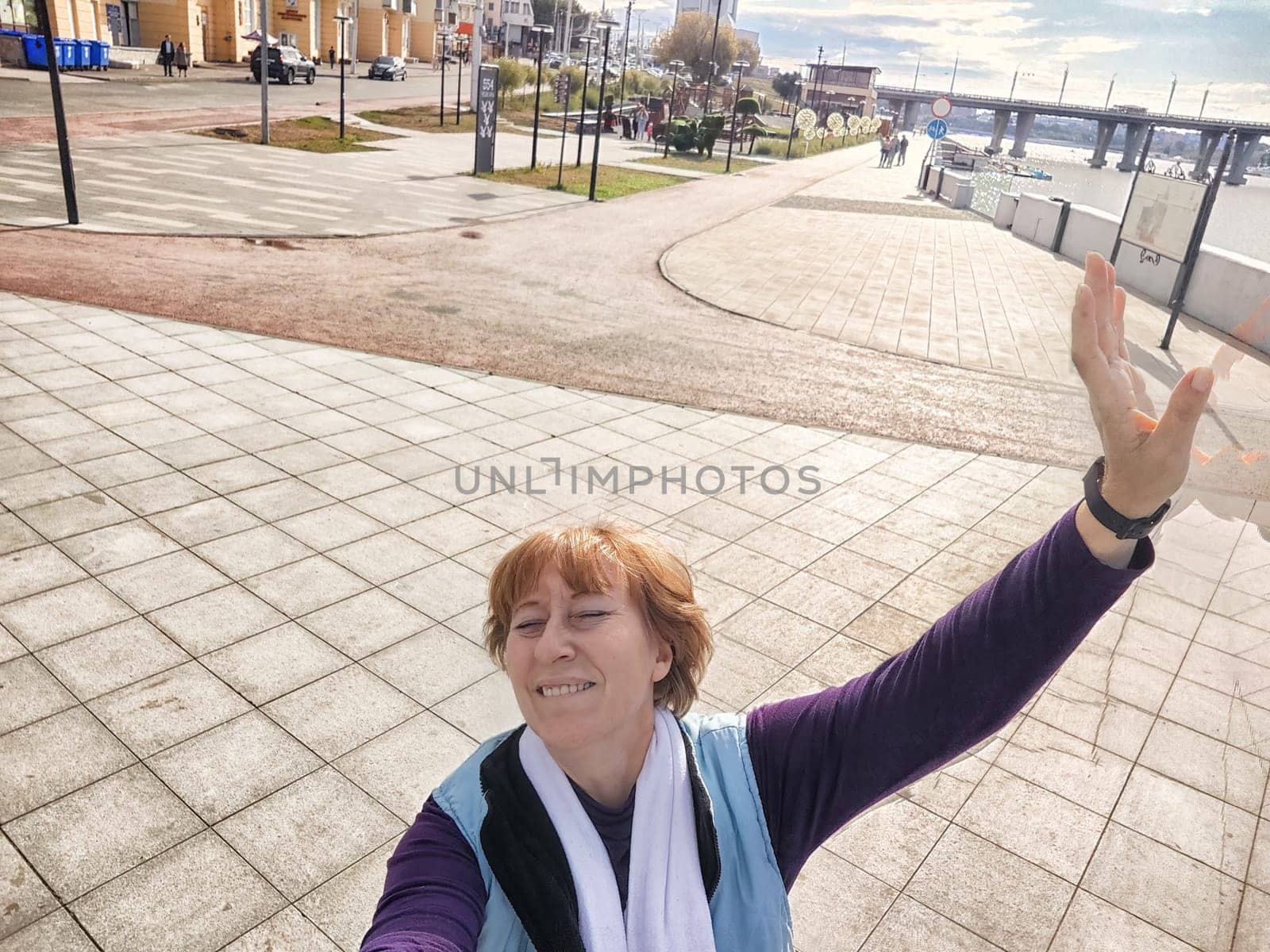 Relaxed mature caucasian female looking at camera and making selfie outside. Positive senior woman against city street background. Adult middle agged girl Blogger posing and taking photo for internet by keleny