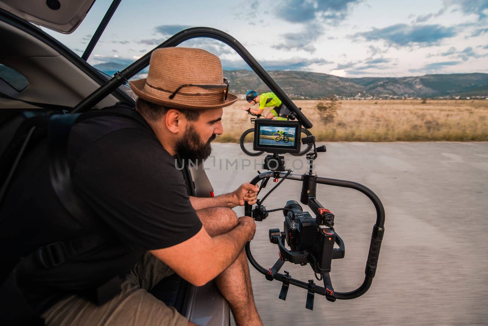 A videographer recording a triathlete riding his bike preparing for an upcoming marathon.Athlete's physical endurance and the dedication required to succeed in the sport