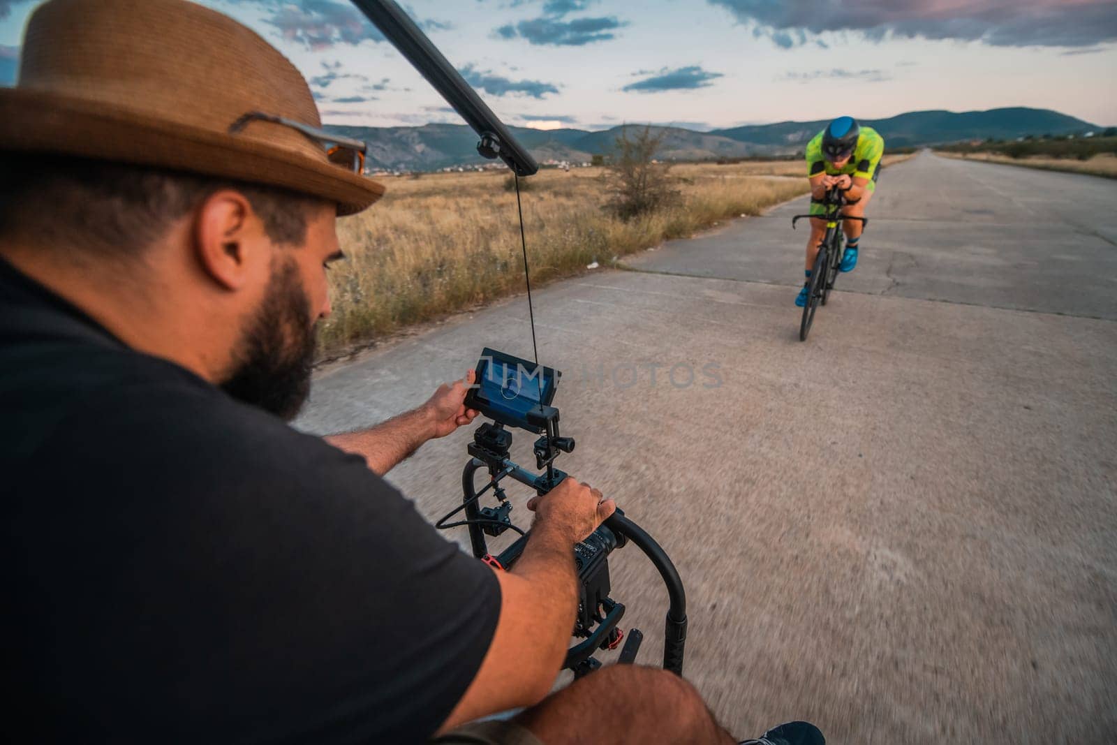 A videographer recording a triathlete riding his bike preparing for an upcoming marathon.Athlete's physical endurance and the dedication required to succeed in the sport. by dotshock