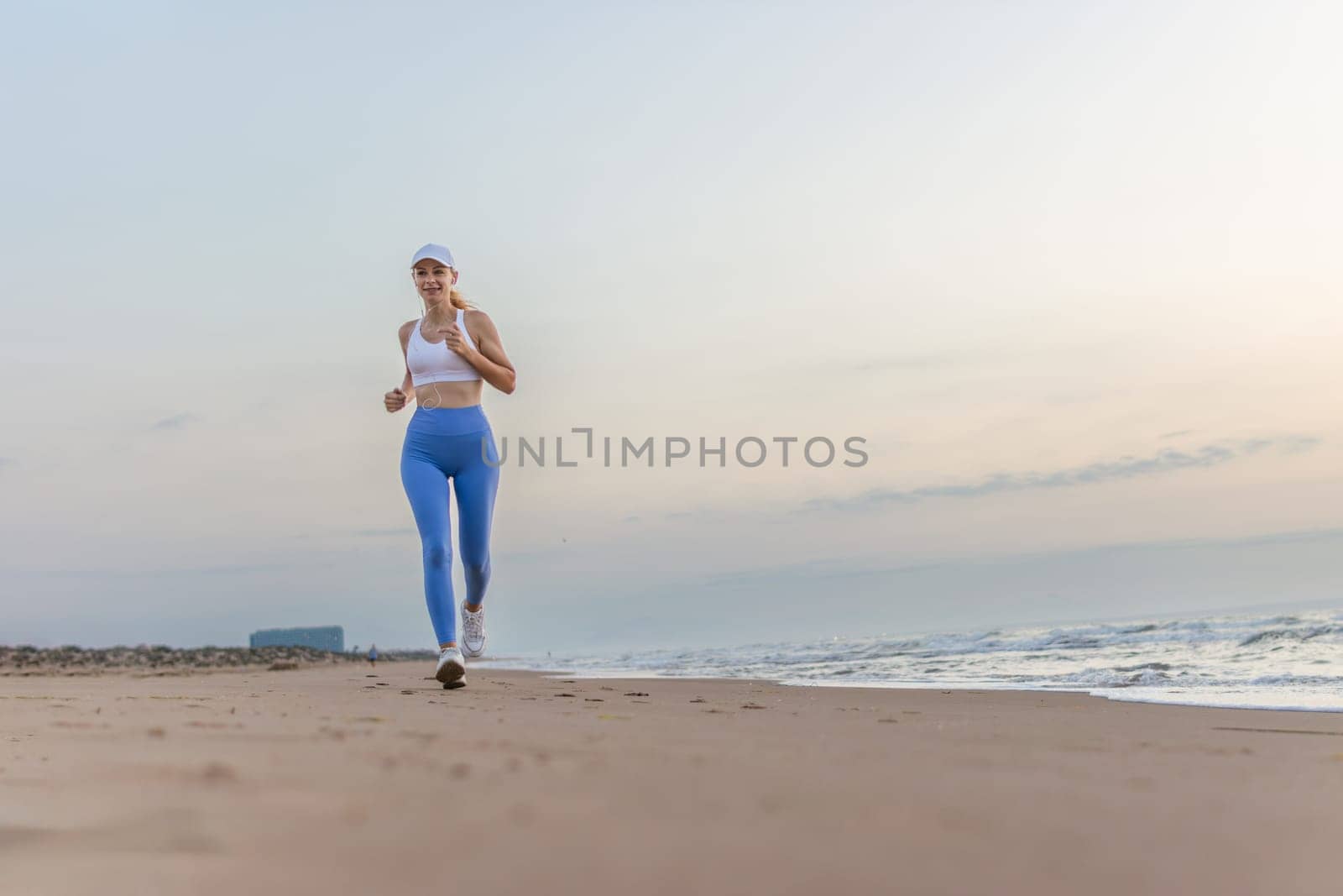 Beautiful sportive woman running along beautiful sandy beach, healthy lifestyle, enjoying active summer vacation near the sea. High quality photo