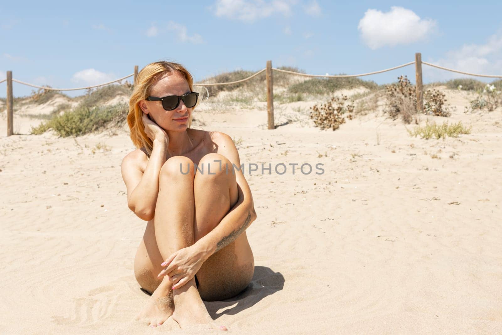 sporty girl sitting on the beach wearing sunglasses, there is a place for the inscription Summer by PopOff