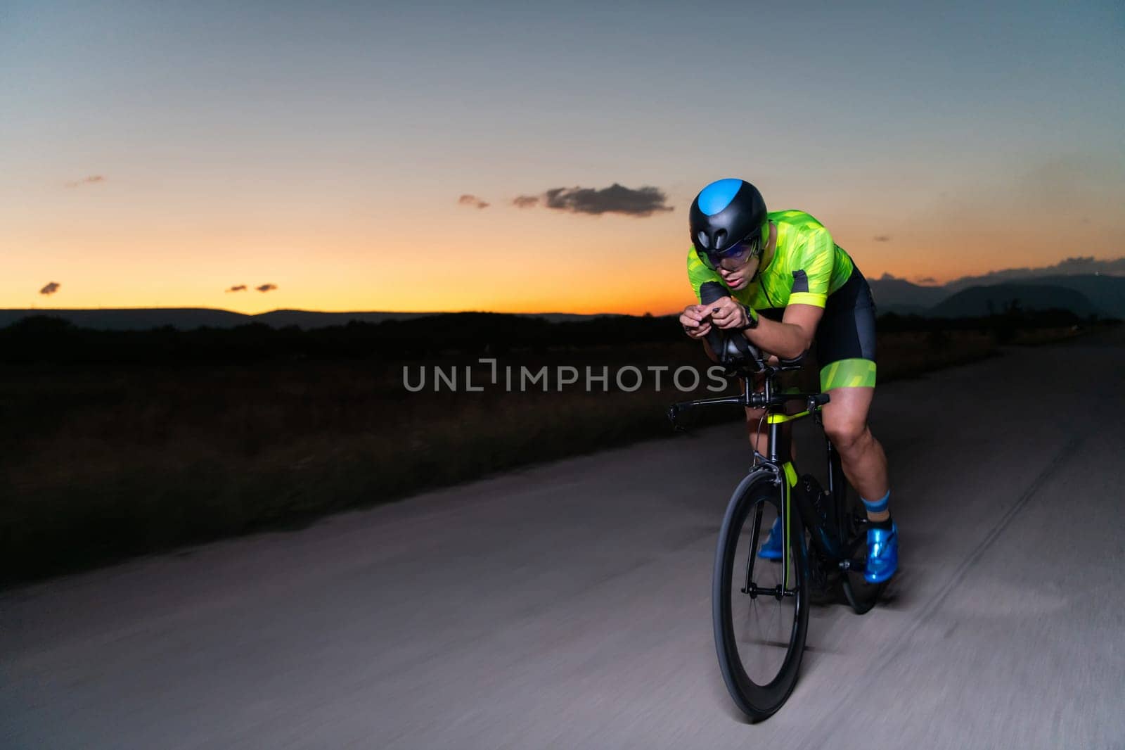 A triathlete rides his bike in the darkness of night, pushing himself to prepare for a marathon. The contrast between the darkness and the light of his bike creates a sense of drama and highlights the athlete's determination and perseverance. by dotshock