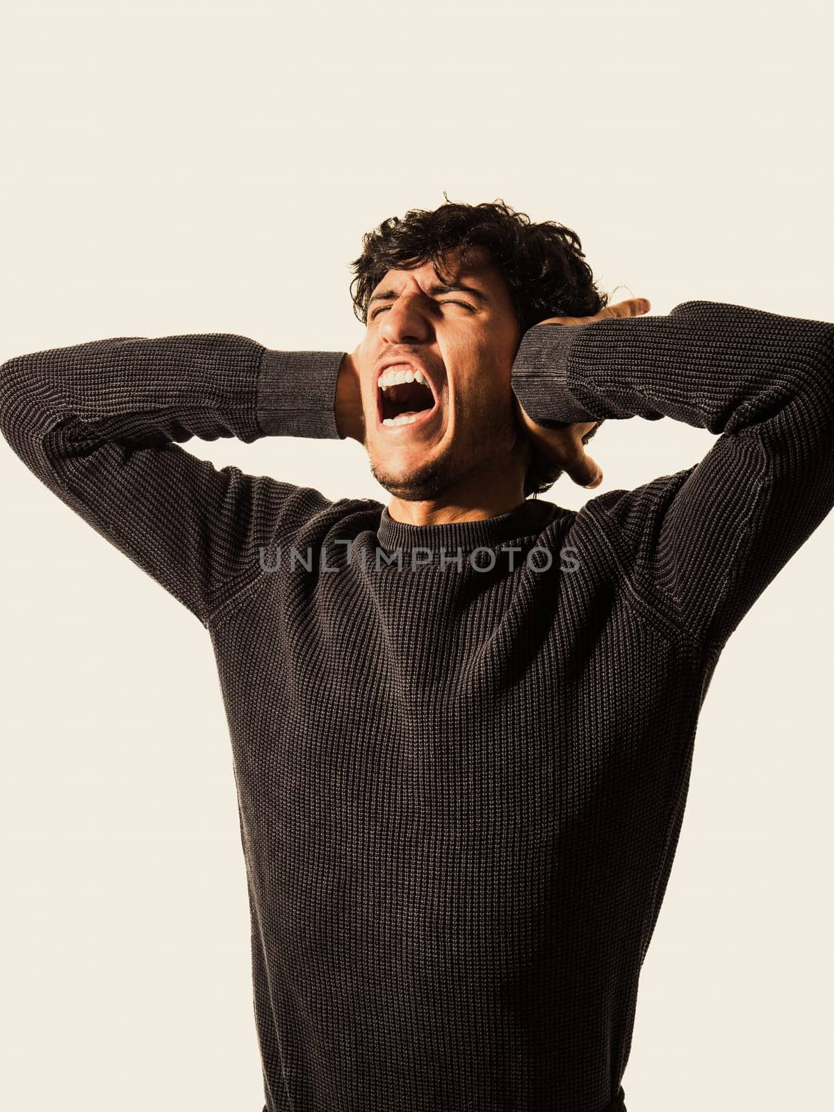 A young man with his hands on his ears, screaming and yelling in despair or frustration