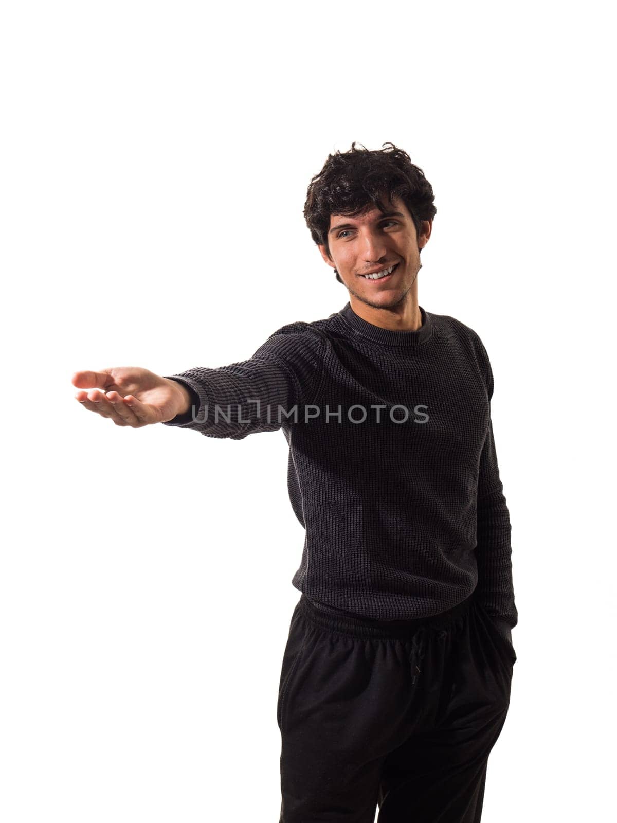 A handsome young man in a black sweater pointing at something, isolated on white