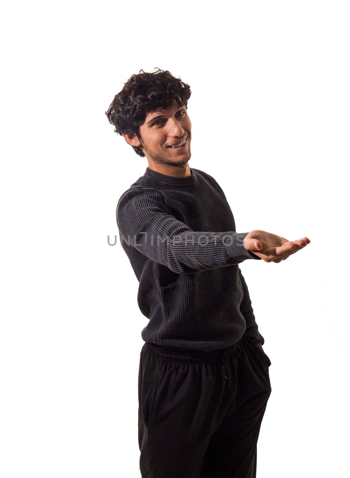 A handsome young man in a black sweater pointing at something, isolated on white