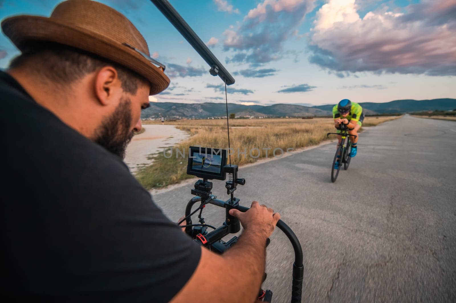 A videographer recording a triathlete riding his bike preparing for an upcoming marathon.Athlete's physical endurance and the dedication required to succeed in the sport