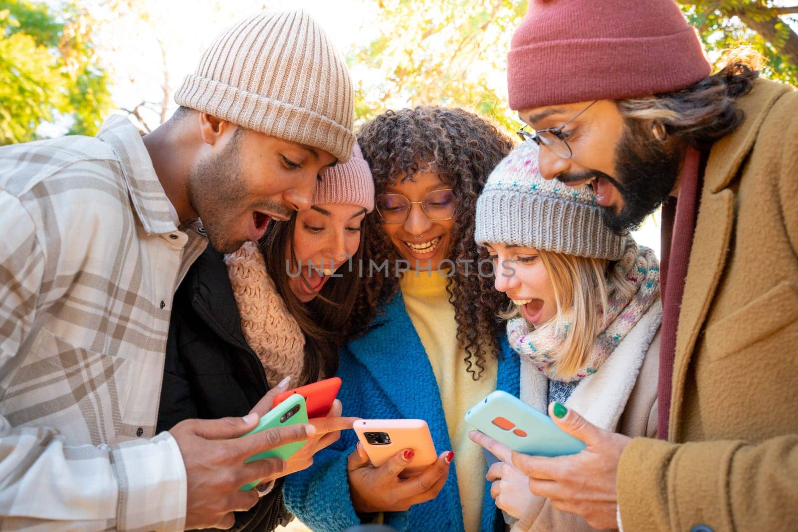 Group of young friends using cell phones surprised expression outdoors. High quality photo