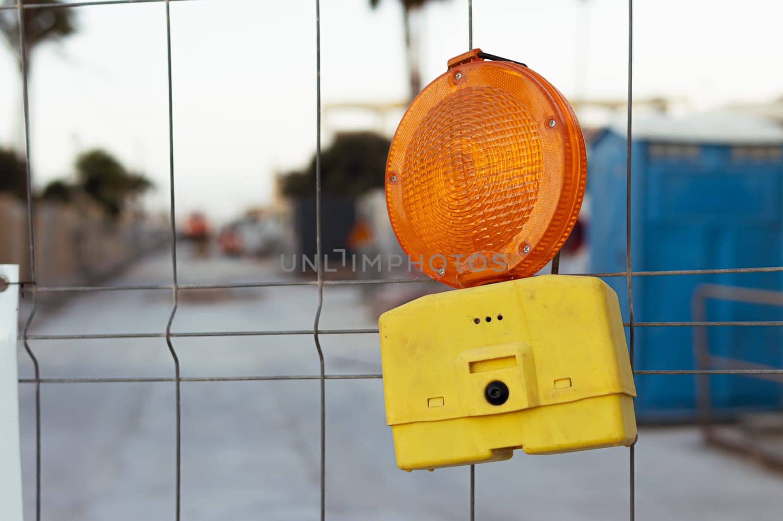 red road construction lamp on the fence indicating attention to work in progress. High quality photo