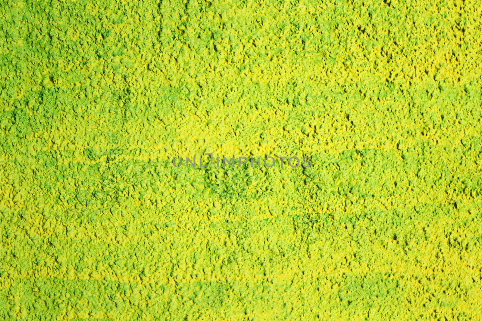 Texture of a wall covered with yellow and green paint, damaged by time. Rough surface of an old painted concrete wall.
