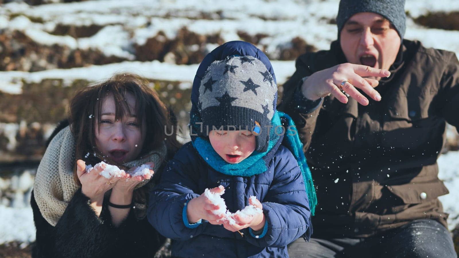 A young, happy family blowing in the snow on a winter's day