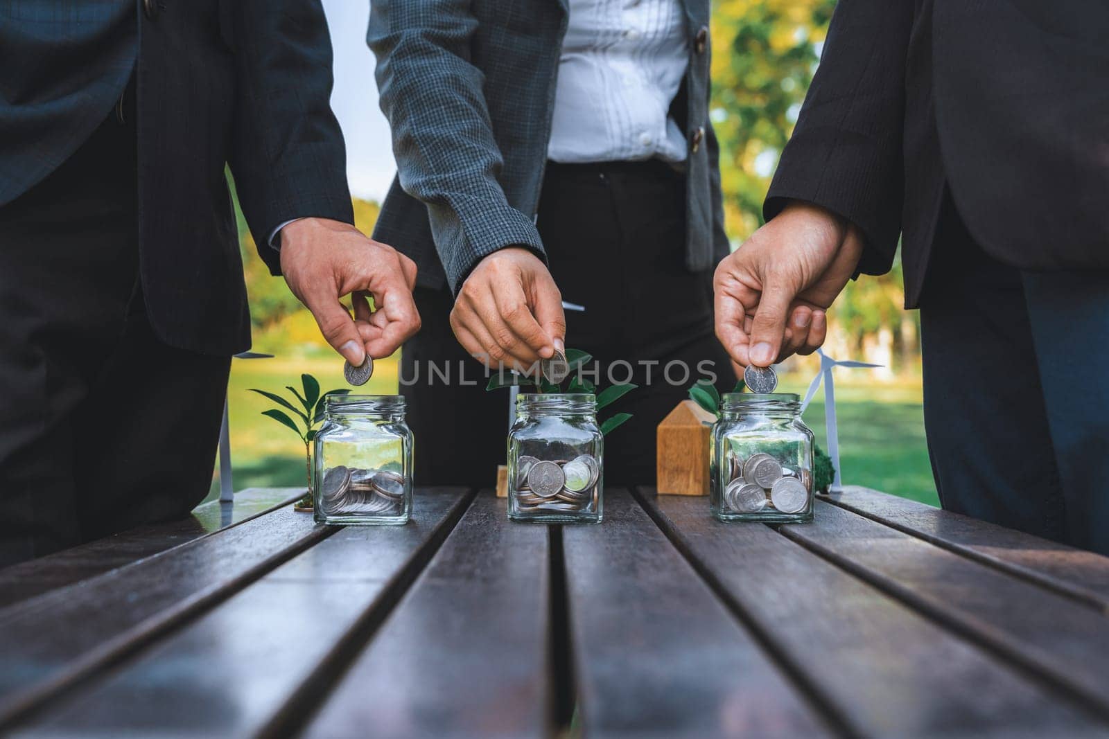 Business people put coin to money saving glass jar on outdoor table as sustainable money growth investment or eco-subsidize. Green corporate promot and invest in environmental awareness. Gyre