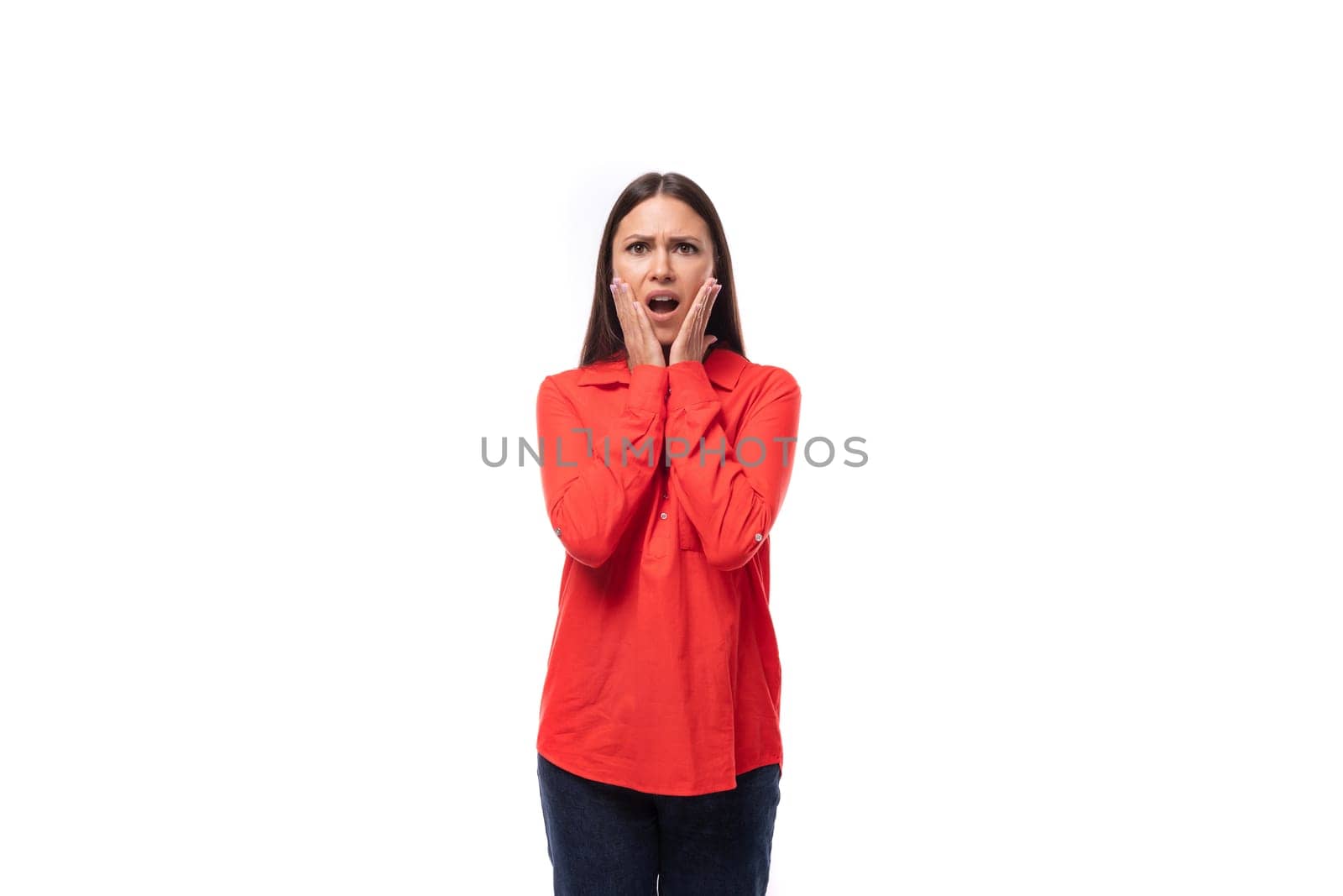 young surprised brunette caucasian model woman dressed in a trendy red shirt is worried on a white background.