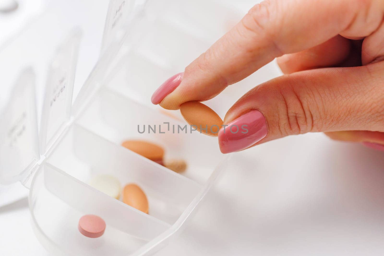 Woman hand taking pill from pillbox or organizer for daily medication. Health care and diseases cure