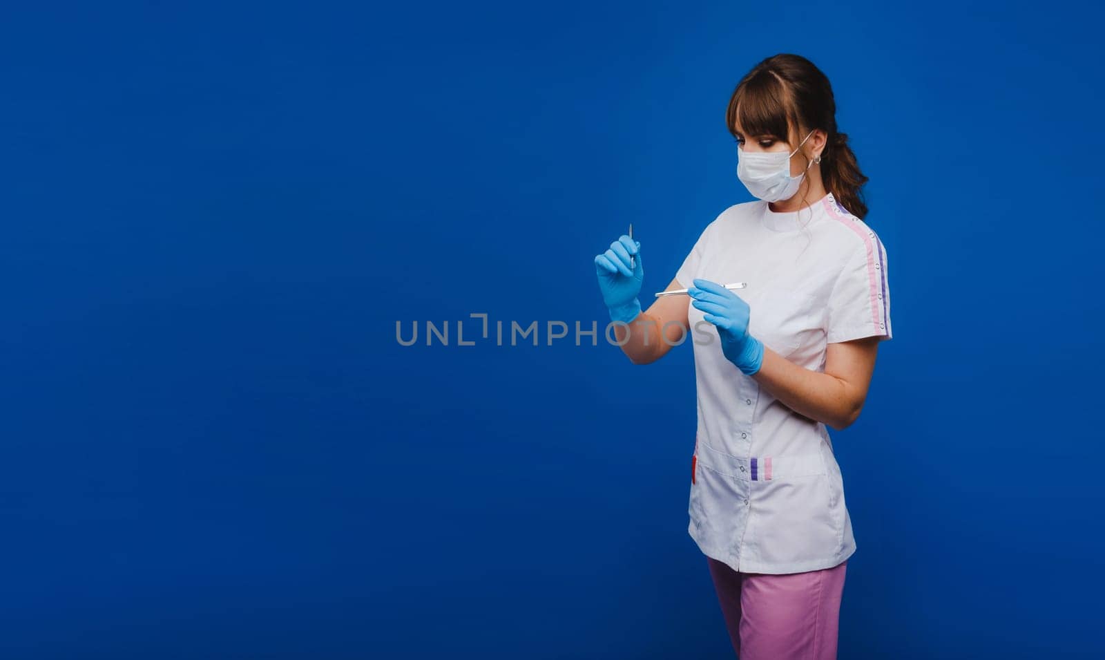 a female surgeon doctor holds a scalpel on a blue background.