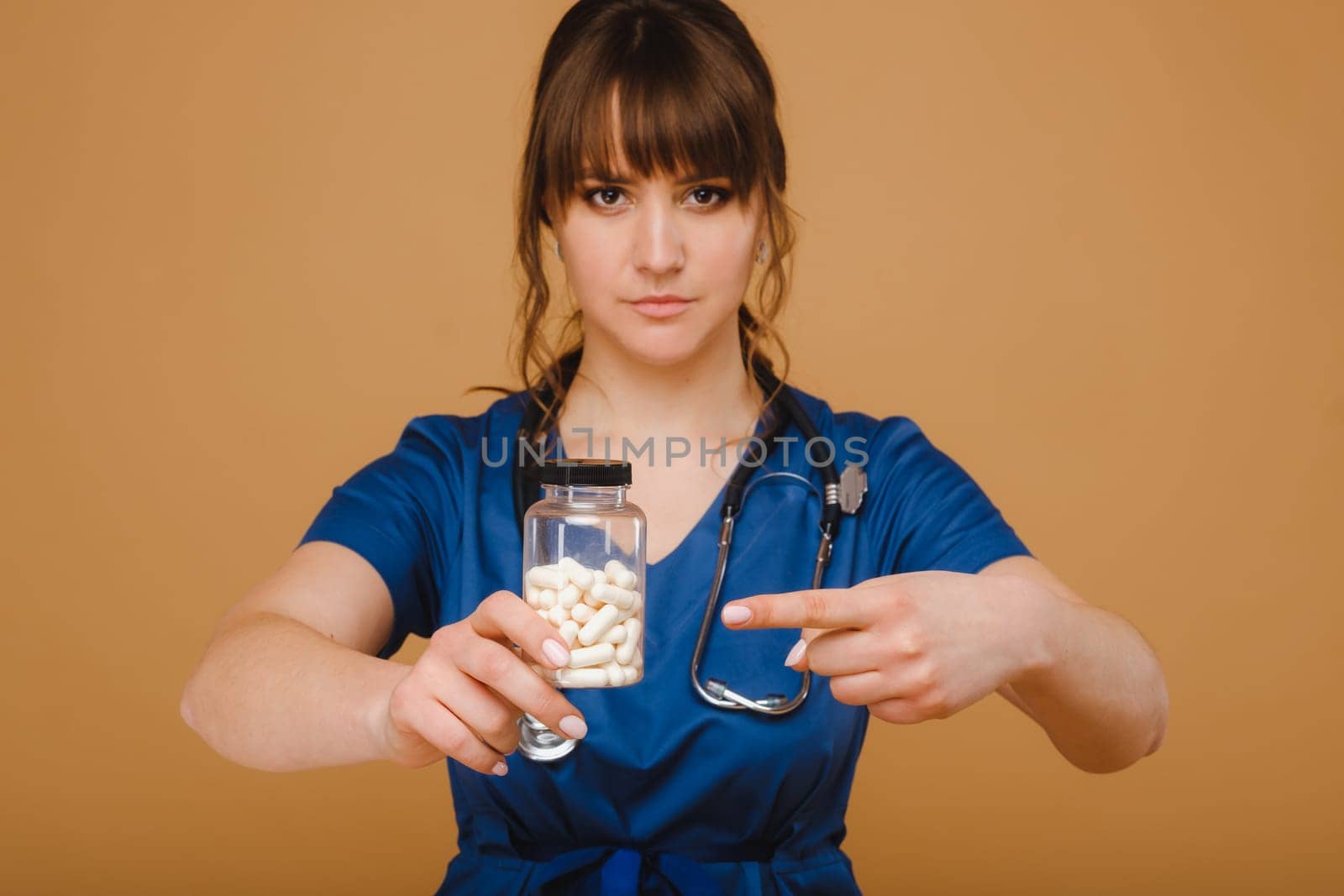 white pills in a jar of a female doctor. The doctor shows the vitamin capsules.Medicinal capsules