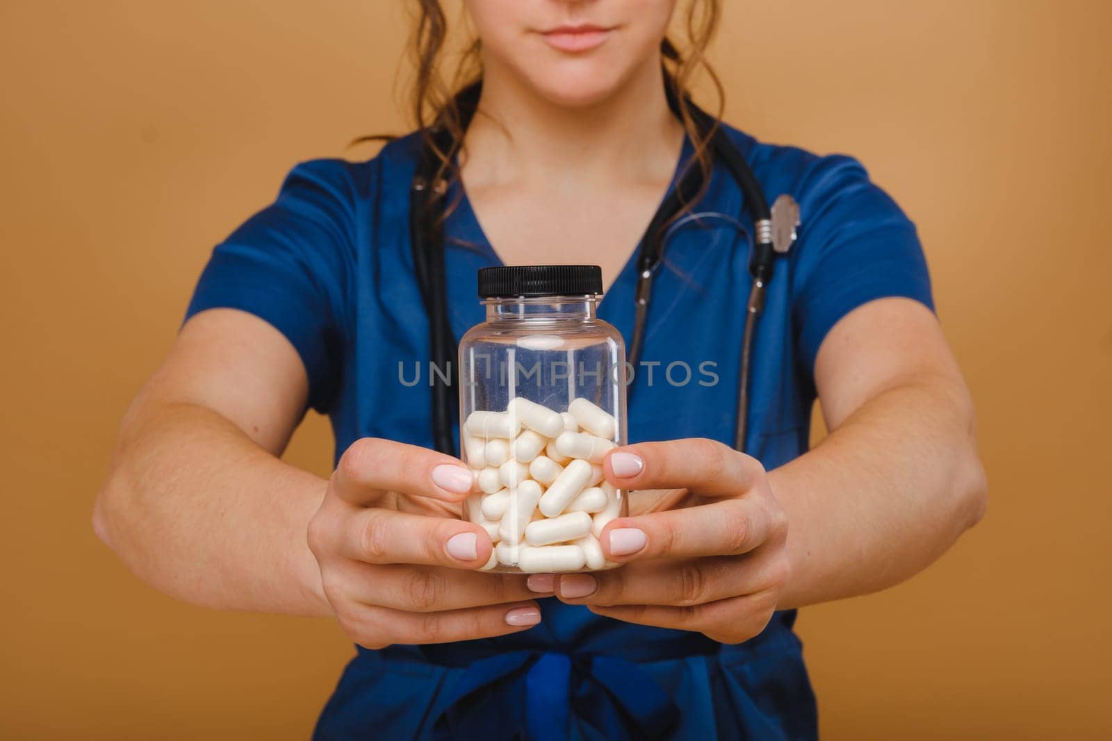 white pills in a jar of a female doctor. The doctor shows the vitamin capsules.Medicinal capsules. by Lobachad
