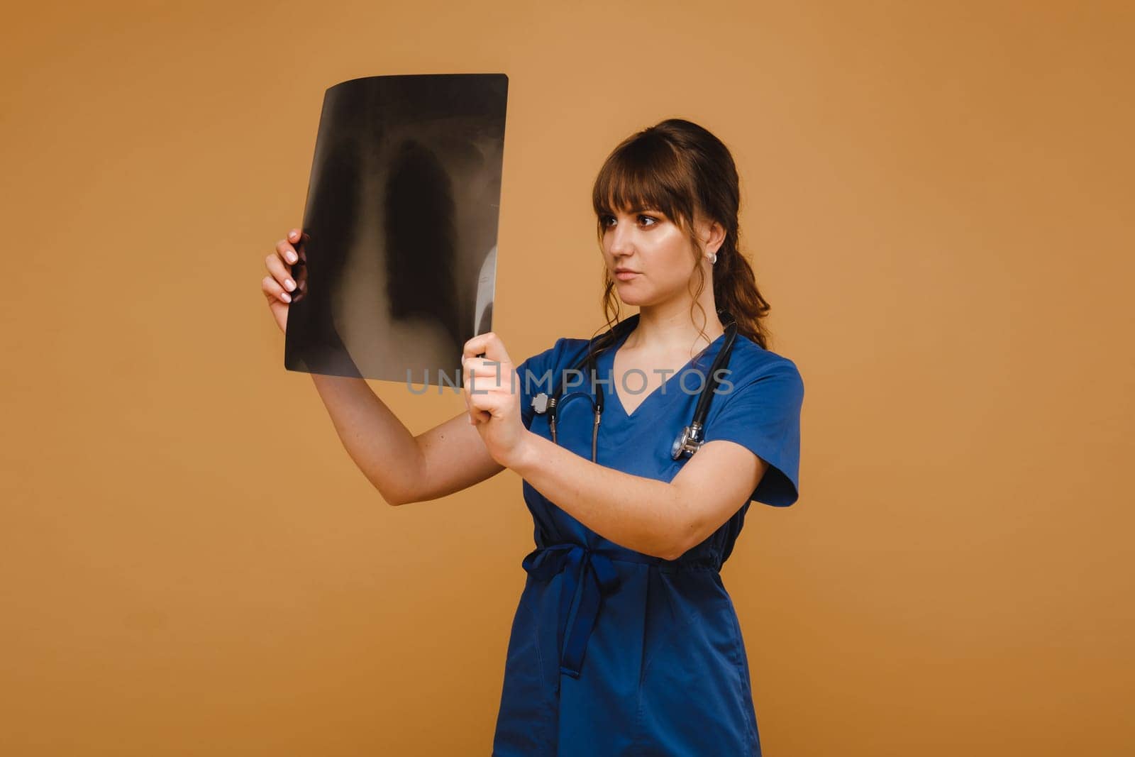 Female Brunette Doctor Looking at Tomography X-ray Film by Lobachad