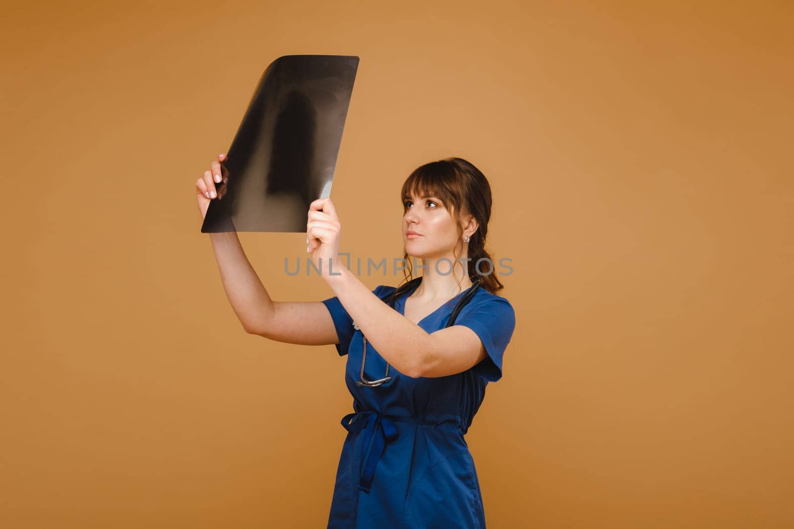 Female Brunette Doctor Looking at Tomography X-ray Film by Lobachad