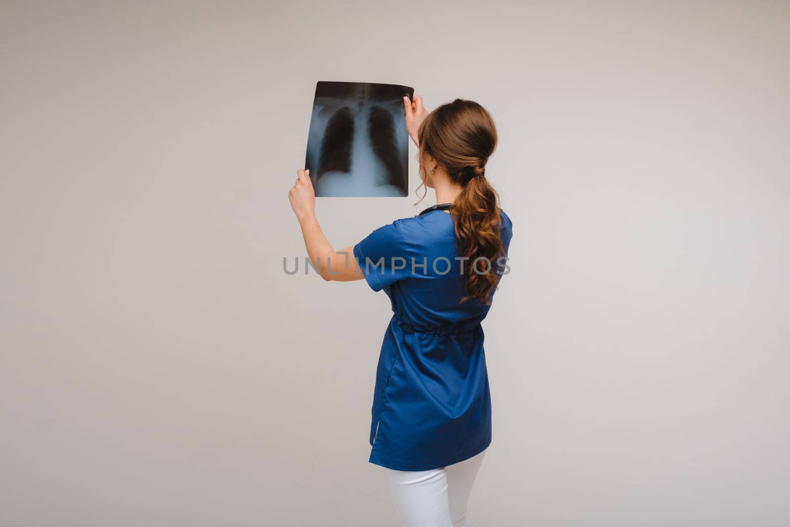 Female Brunette Doctor Looking at Tomography X-ray Film by Lobachad